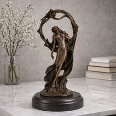 Art Nouveau bronze woman sculpture holding an orb, ethereal maiden statue with billowing gown and floral arch on black marble base, loss wax casting fine art.