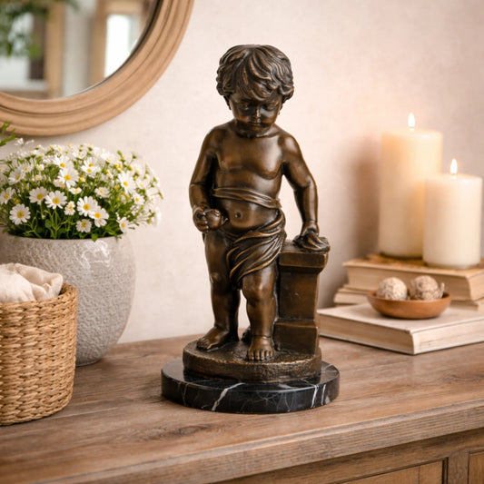 Classical bronze putto statue of a young boy holding fruit, curly-haired cherub sculpture on veined black marble base, loss wax casting figurative art for home library.