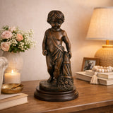 Classical bronze putto statue with overflowing cornucopia fruit, curly-haired cherub sculpture on stepped black marble base, loss wax casting harvest art.