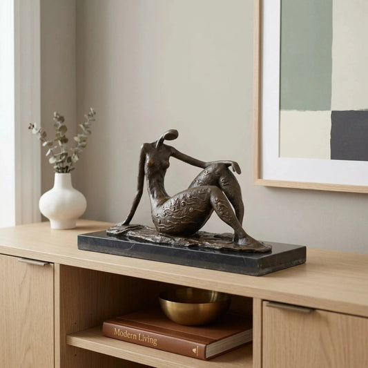 Contemporary abstract bronze seated female sculpture with golden swirls, faceless elongated woman statue on black marble base, loss wax casting modern art.