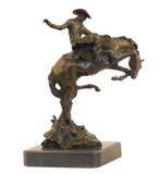 Bronze reproduction of Frederic Remington's Broncho Buster statue, cowboy riding a bucking horse on black marble base, loss wax casting fine art.
