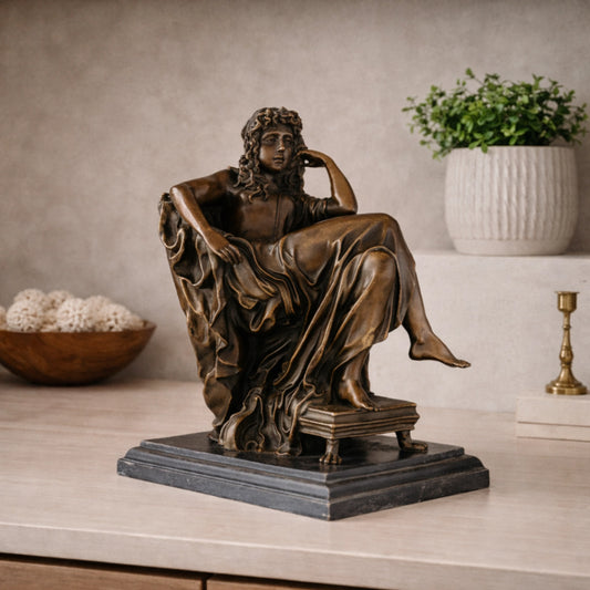 Stunning classical bronze sculpture of a seated muse in contemplative pensiero pose, goddess with flowing robes on claw-foot pedestal and black marble base, loss wax casting fine art.