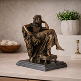 Stunning classical bronze sculpture of a seated muse in contemplative pensiero pose, goddess with flowing robes on claw-foot pedestal and black marble base, loss wax casting fine art.