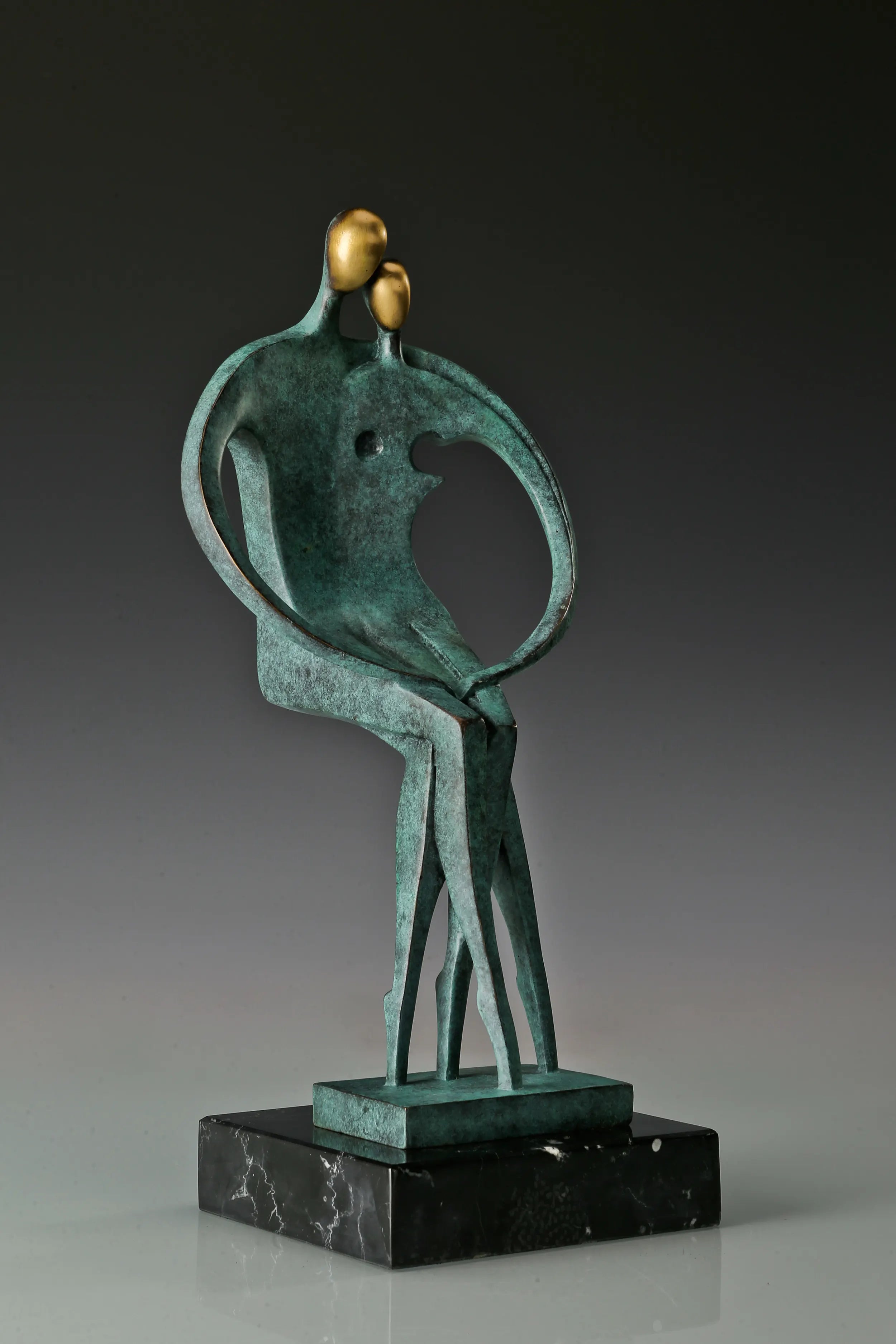 Three-quarter view of abstract bronze lovers statue on a polished black marble base