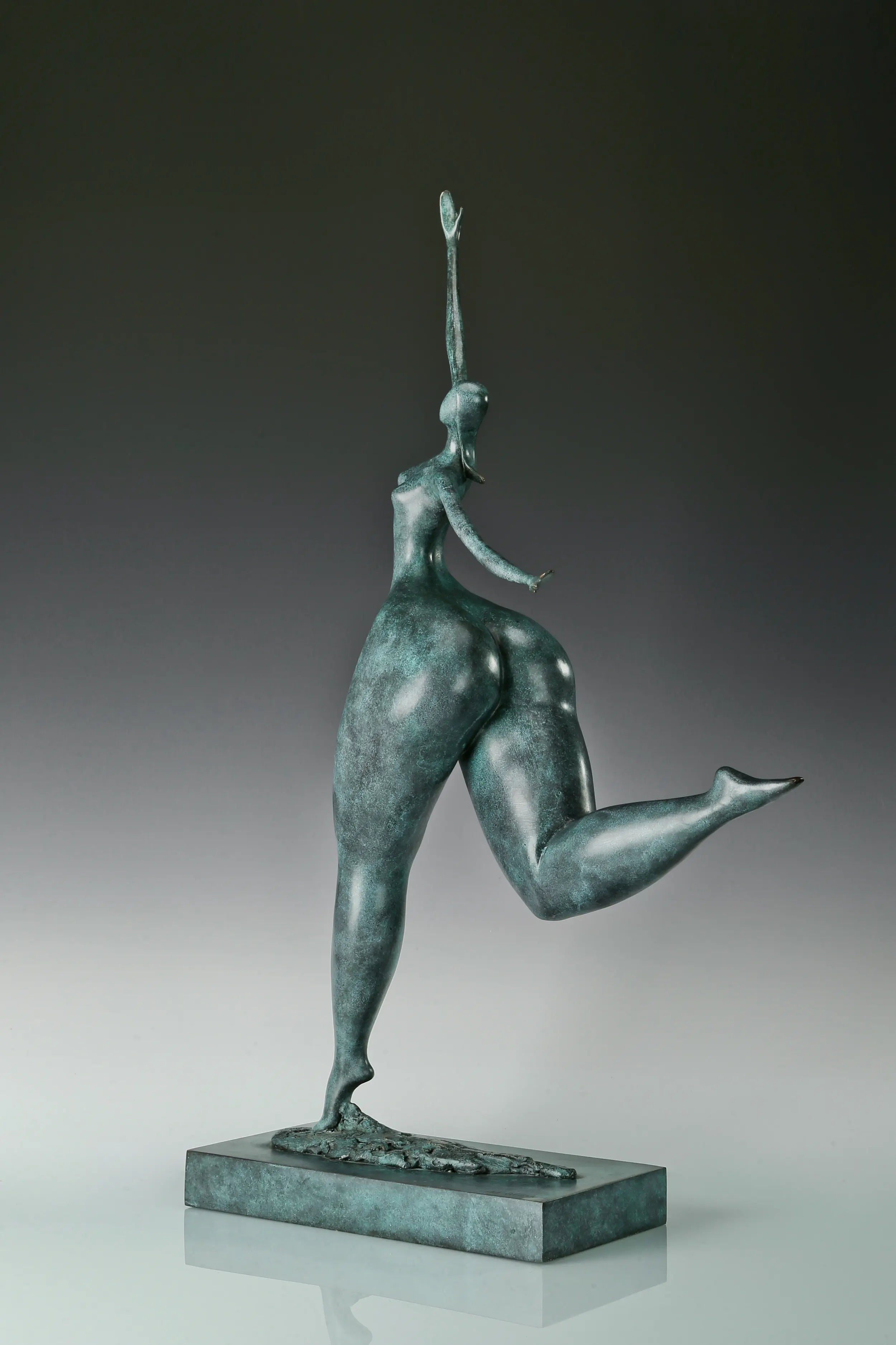 Angled view of modern abstract dancing woman bronze sculpture with green bronze patina