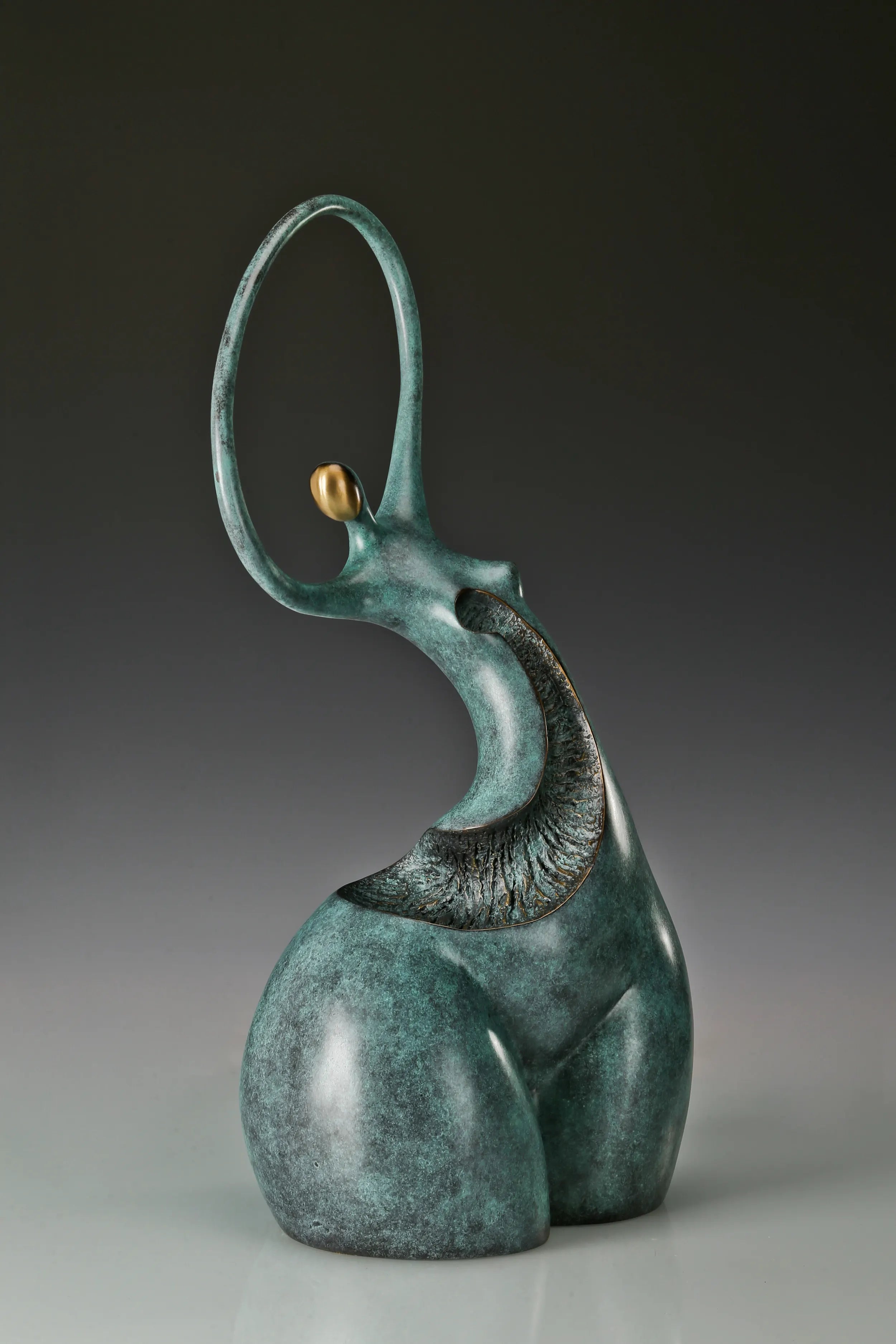 Three-quarter view of abstract female bronze sculpture with gold-toned facial accent