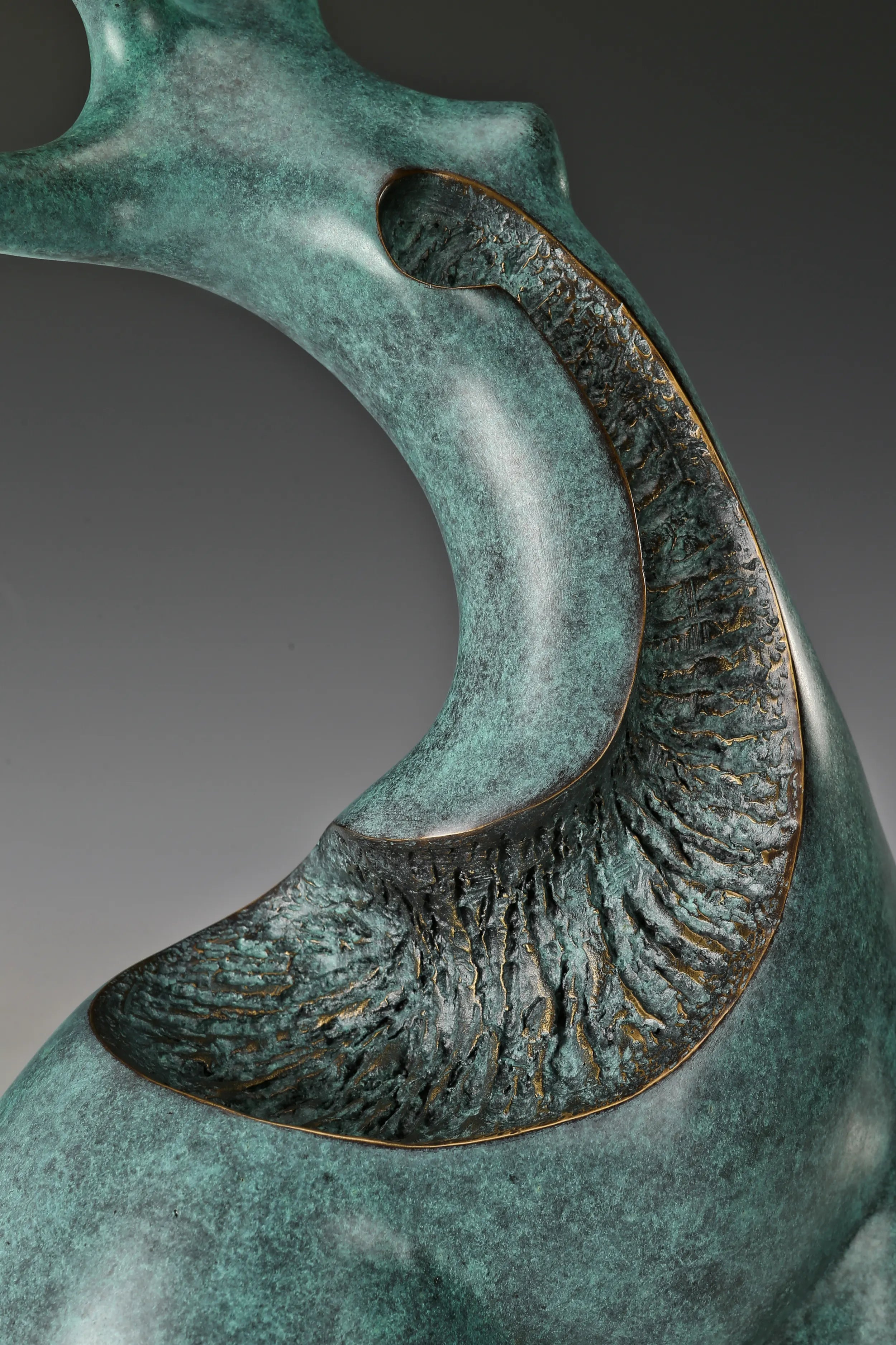 Close-up of textured openwork section and curved bronze surface with green patina