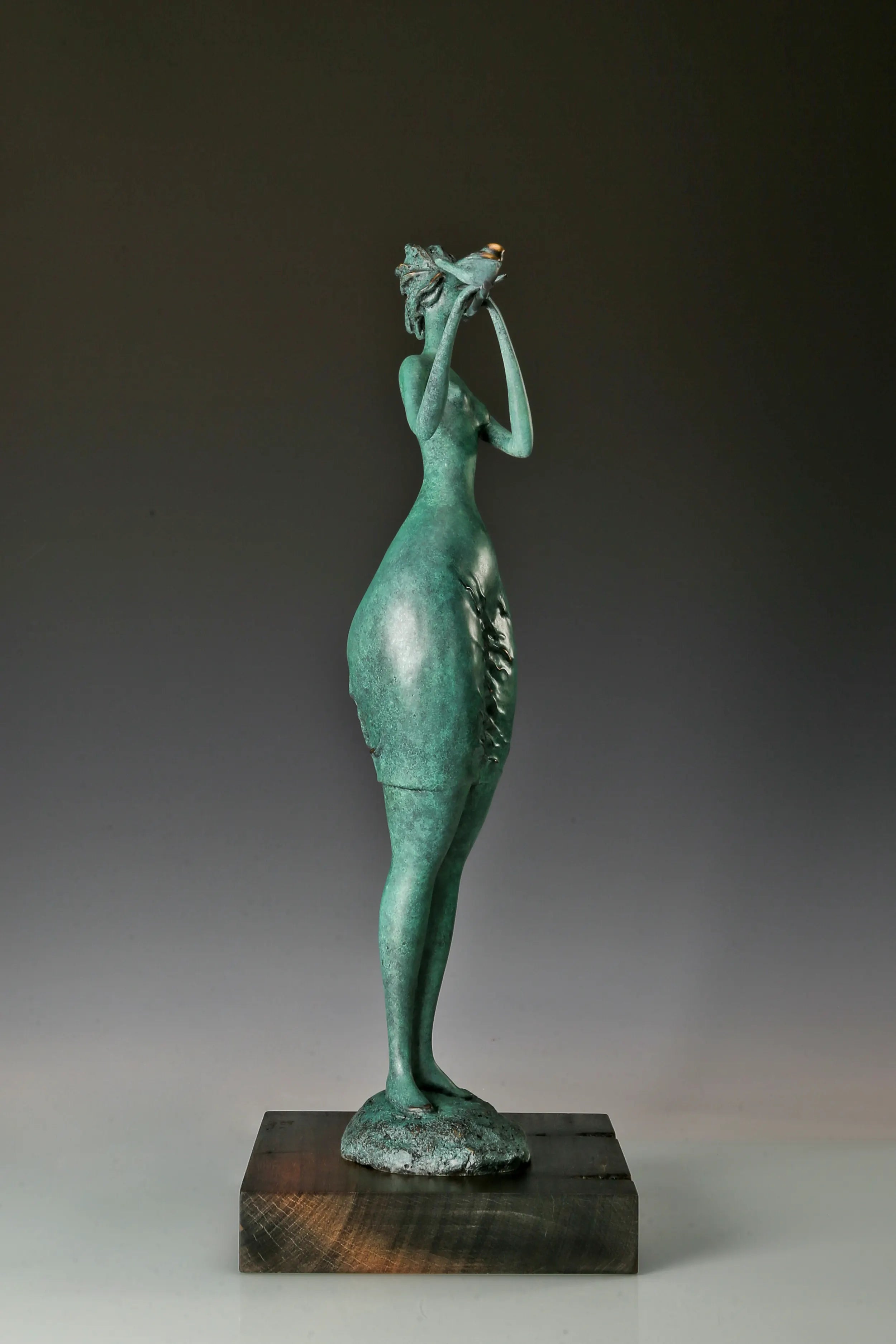 Left side view of an elongated female musician sculpture with green bronze patina