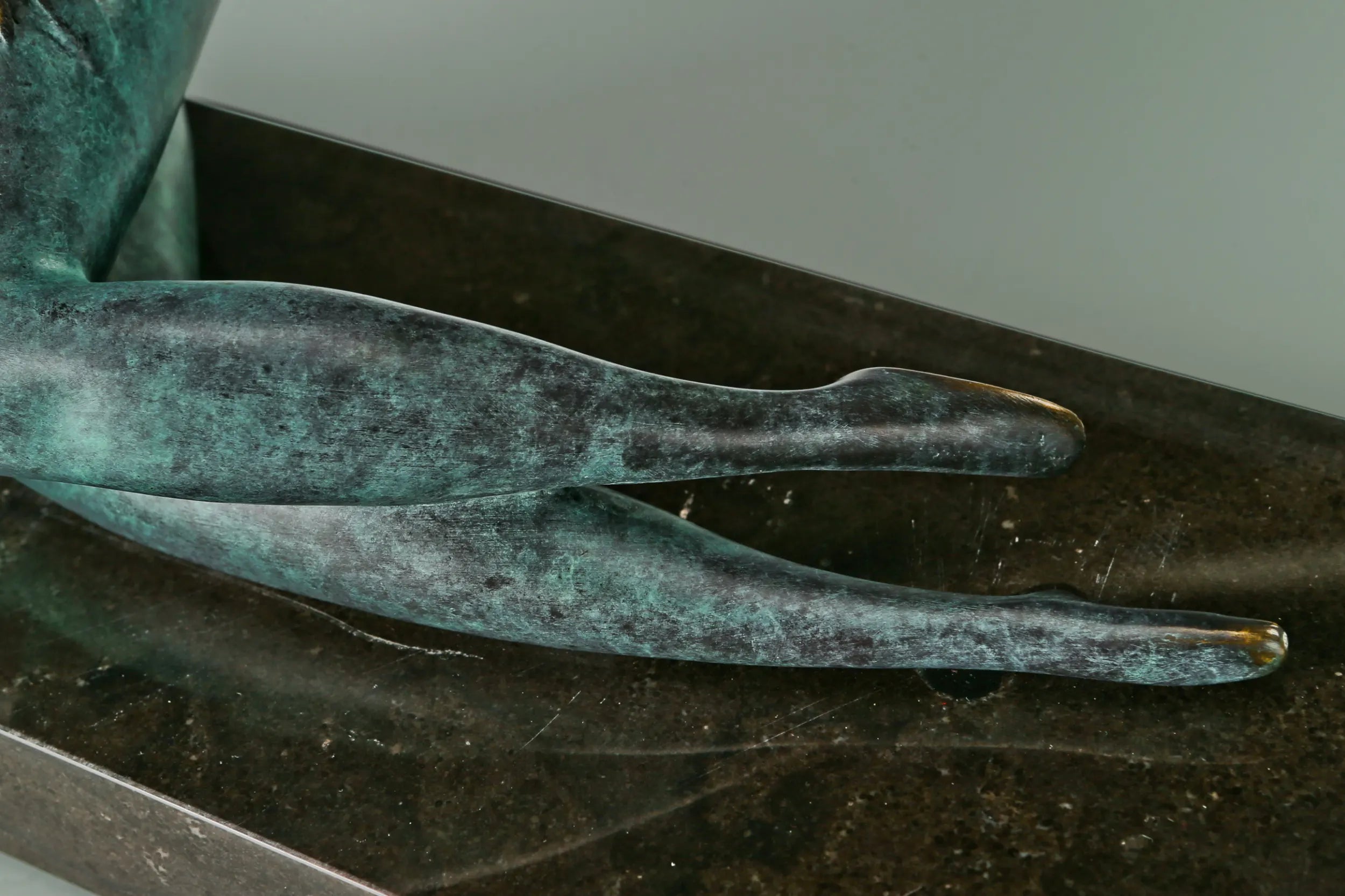 Detail of the reclining bronze woman's overlapping legs and feet