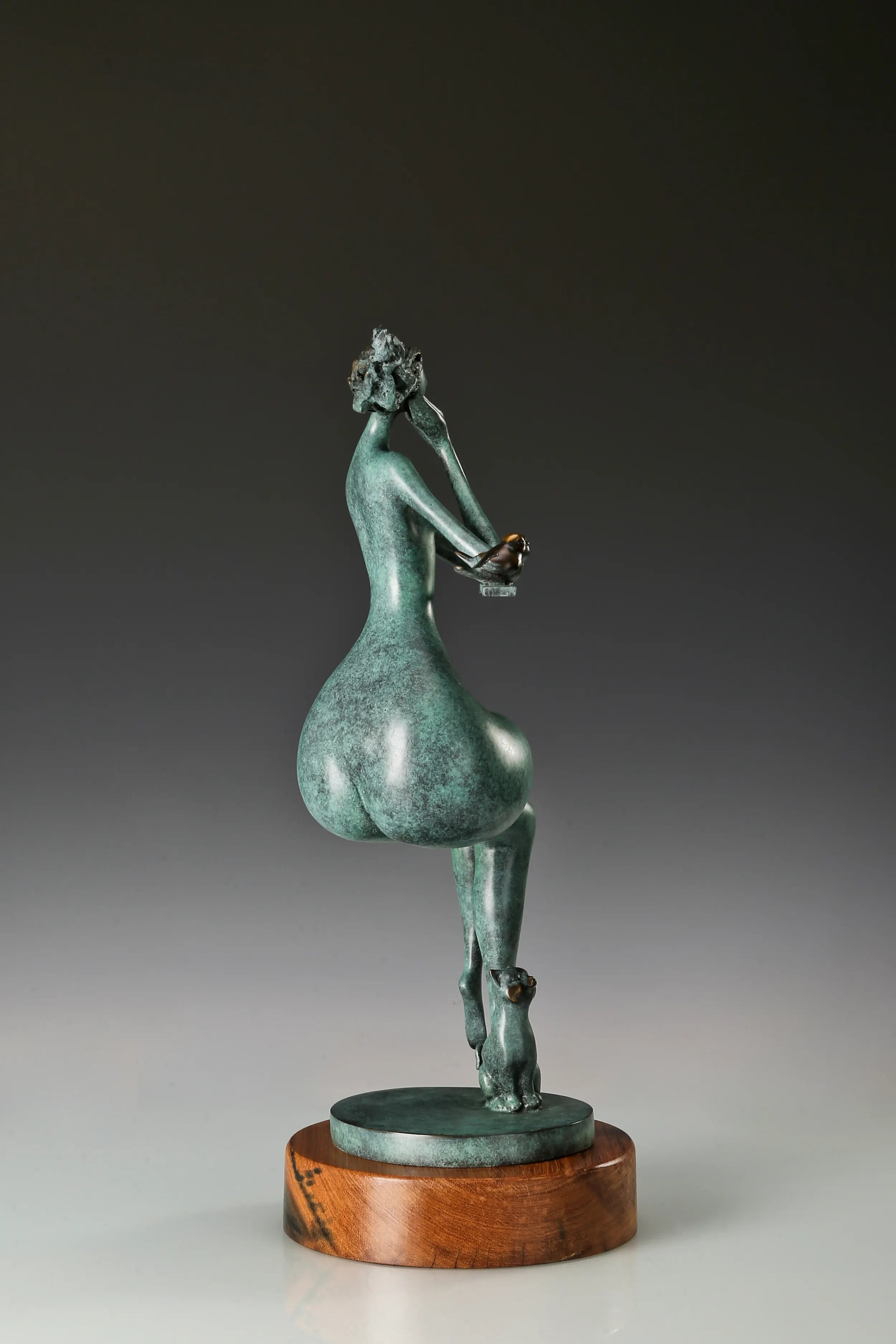 Opposite side view of the abstract seated woman bronze sculpture with green patina