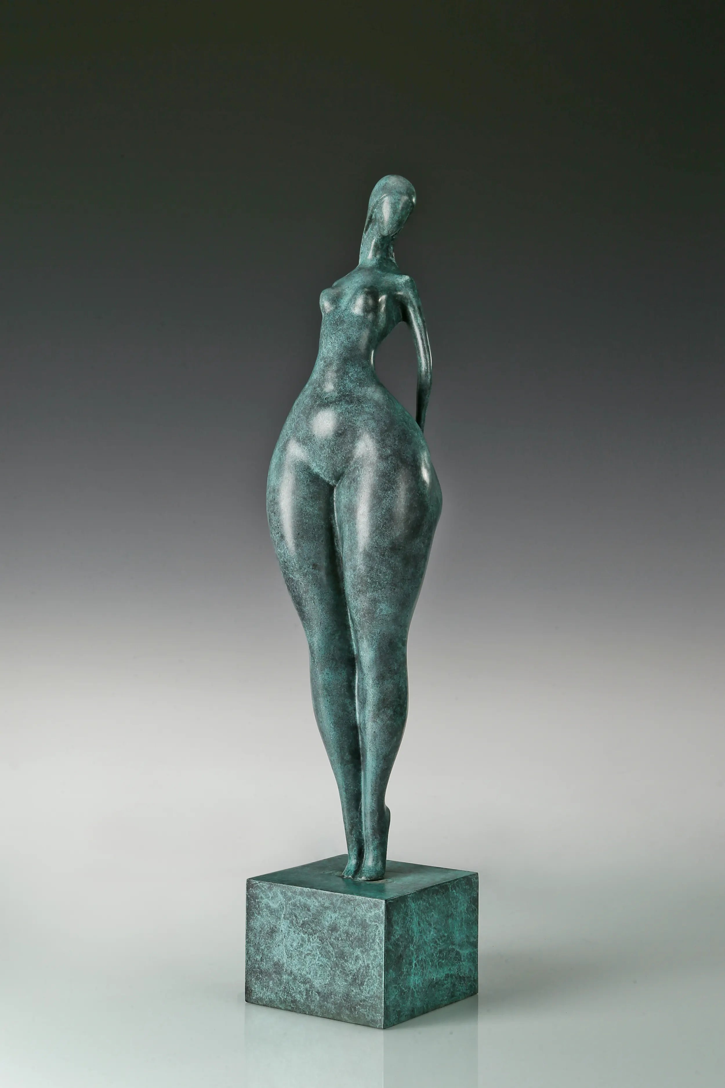 Front view of abstract standing female bronze figure with elongated proportions and green patina