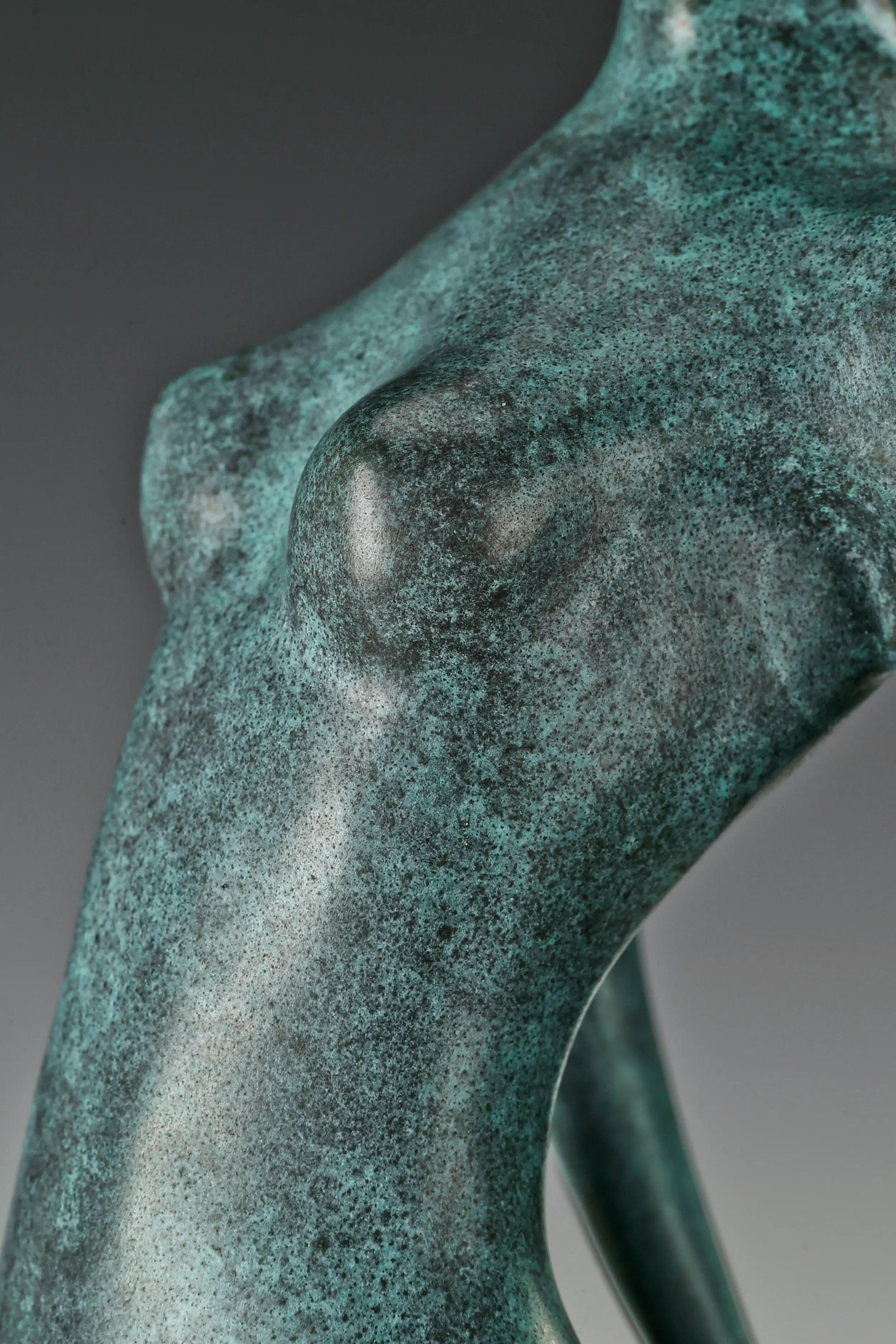 Close-up of the sculpted torso and textured green patina on the abstract female figure