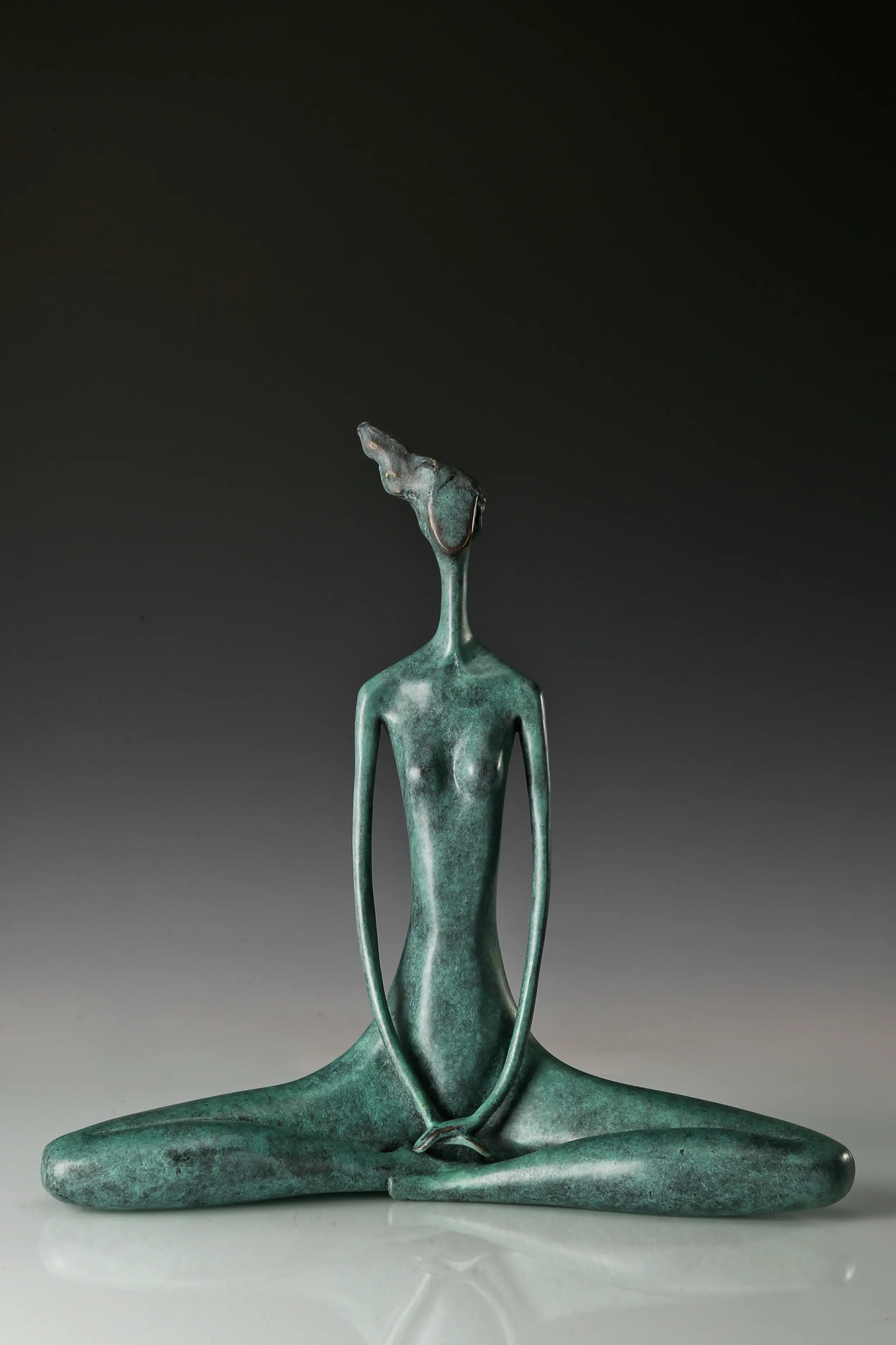Full view of green bronze seated meditation sculpture with long slender arms