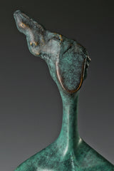 Close-up of abstract woman's upward-tilted head and textured bronze patina