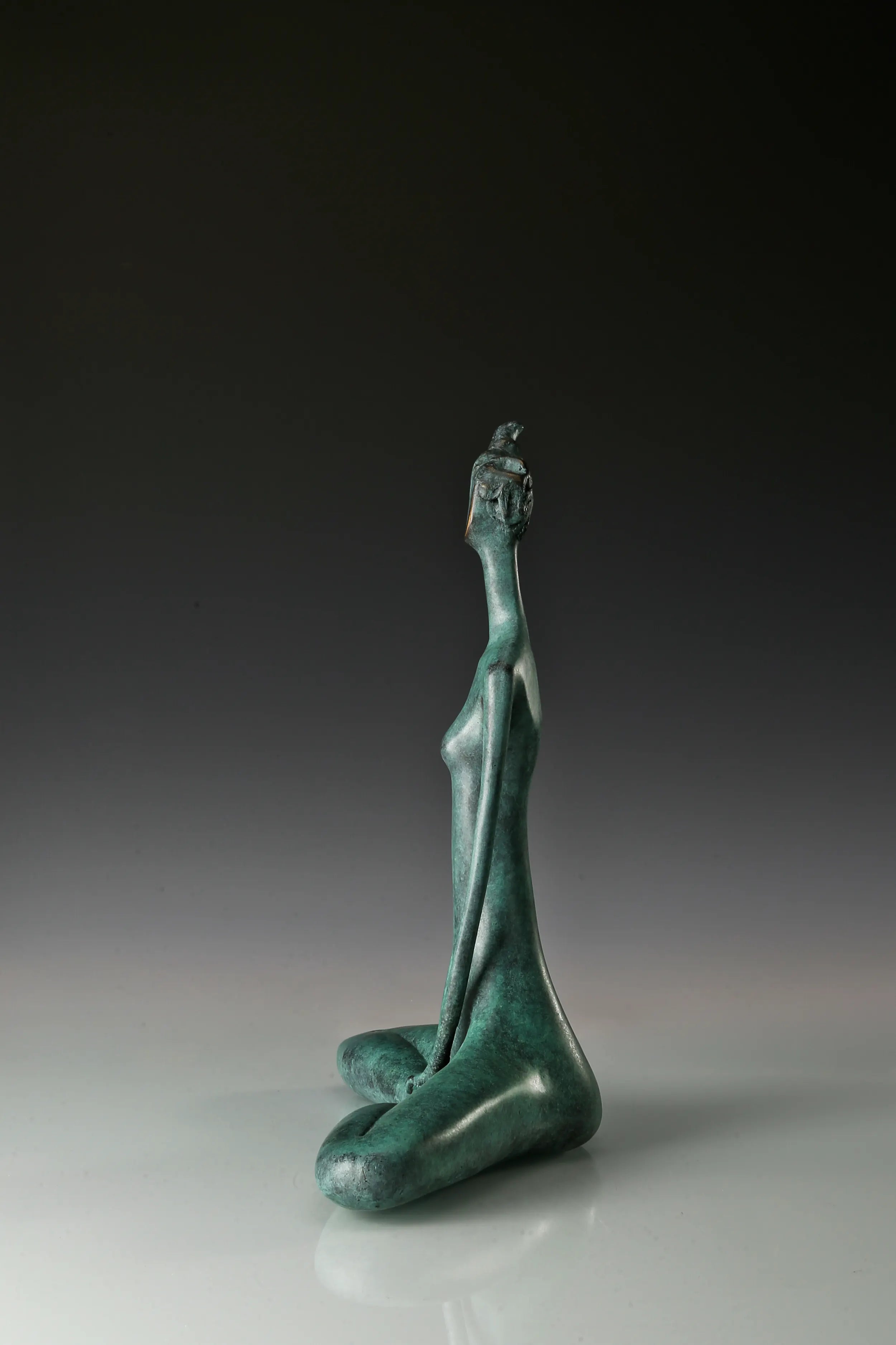 Side profile of abstract bronze yoga woman with an elongated neck and seated pose
