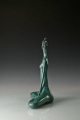 Side profile of abstract bronze yoga woman with an elongated neck and seated pose