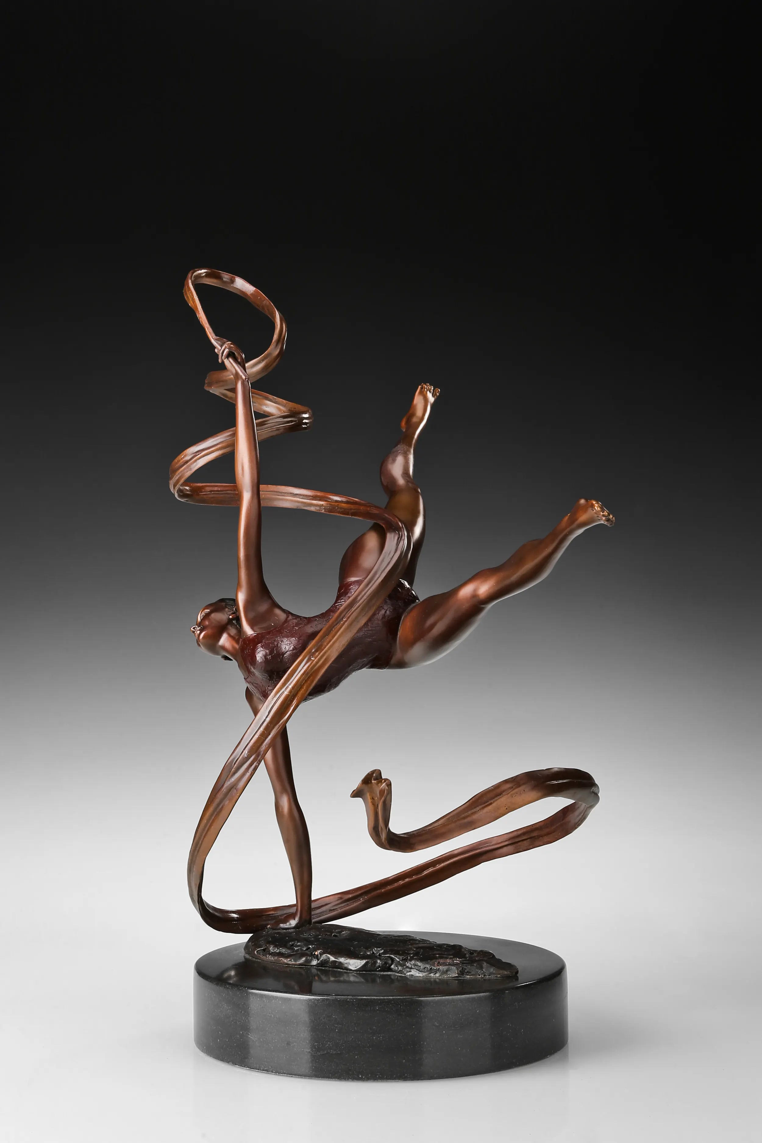 Angled view of bronze ballet dancer sculpture with an extended leg and spiral ribbon