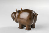 Side view of a solid bronze cartoon cow statue with a warm bronze patina.