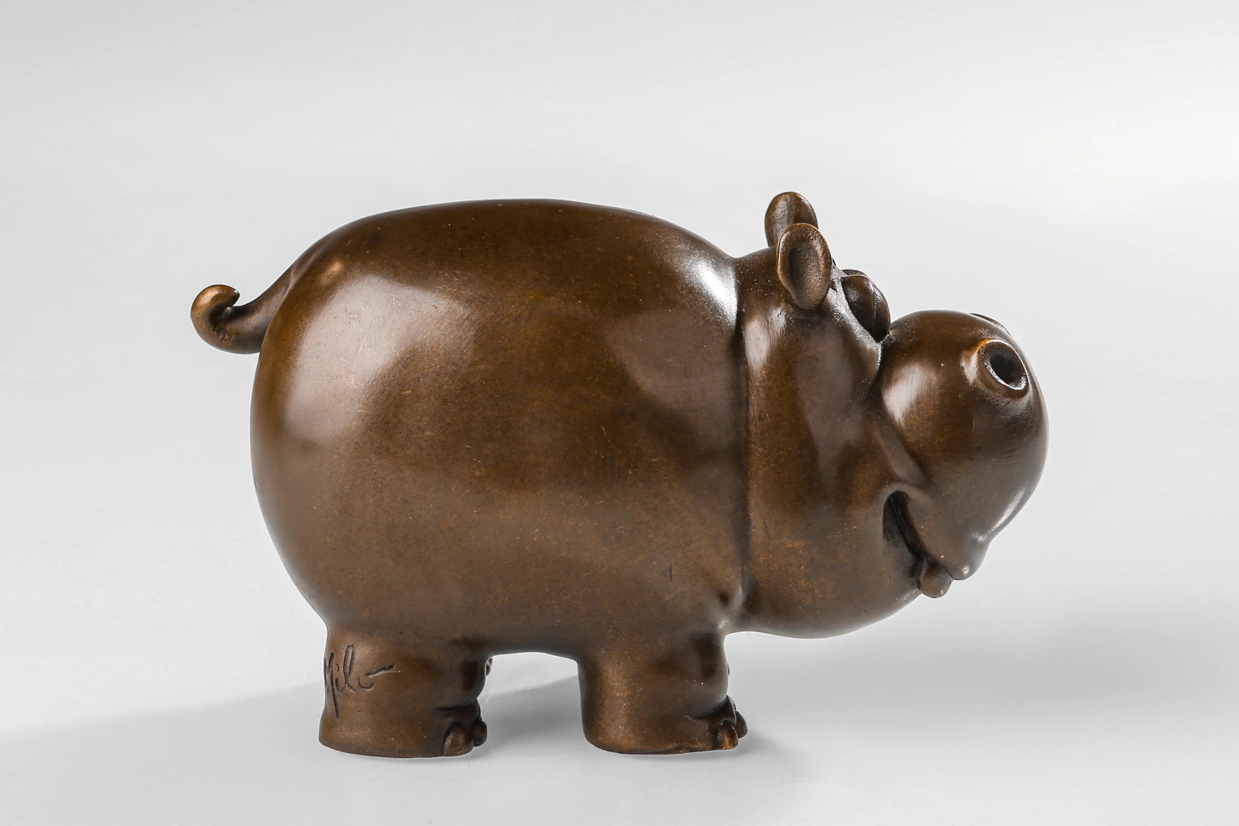 Right side view of a handcrafted bronze cow sculpture with a playful expression.