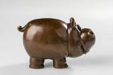 Right side view of a handcrafted bronze cow sculpture with a playful expression.