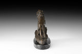 Rear view of bronze lion sculpture showing muscular hindquarters, tail, and textured rocky base