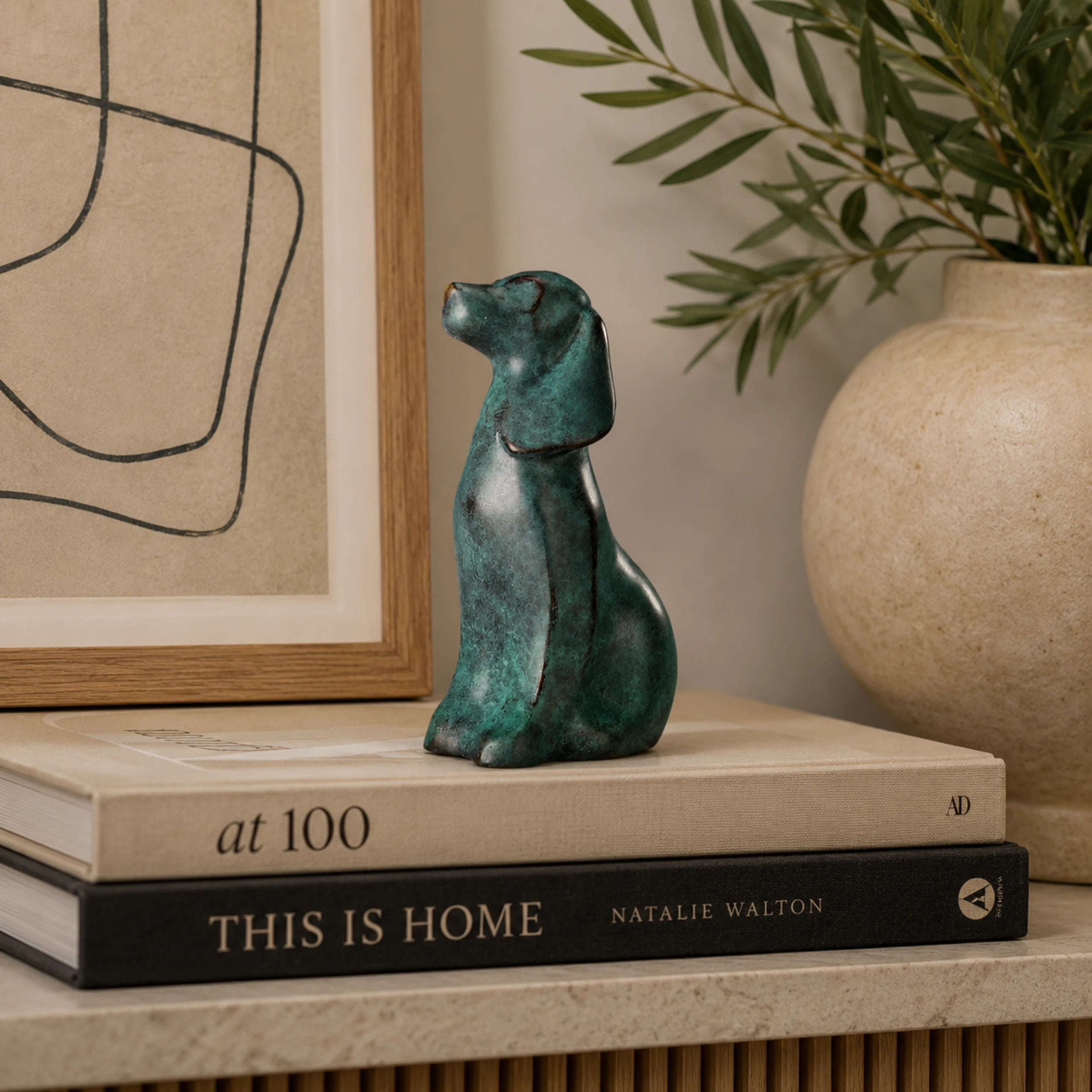 Green patina bronze seated dog sculpture displayed as modern shelf and home decor
