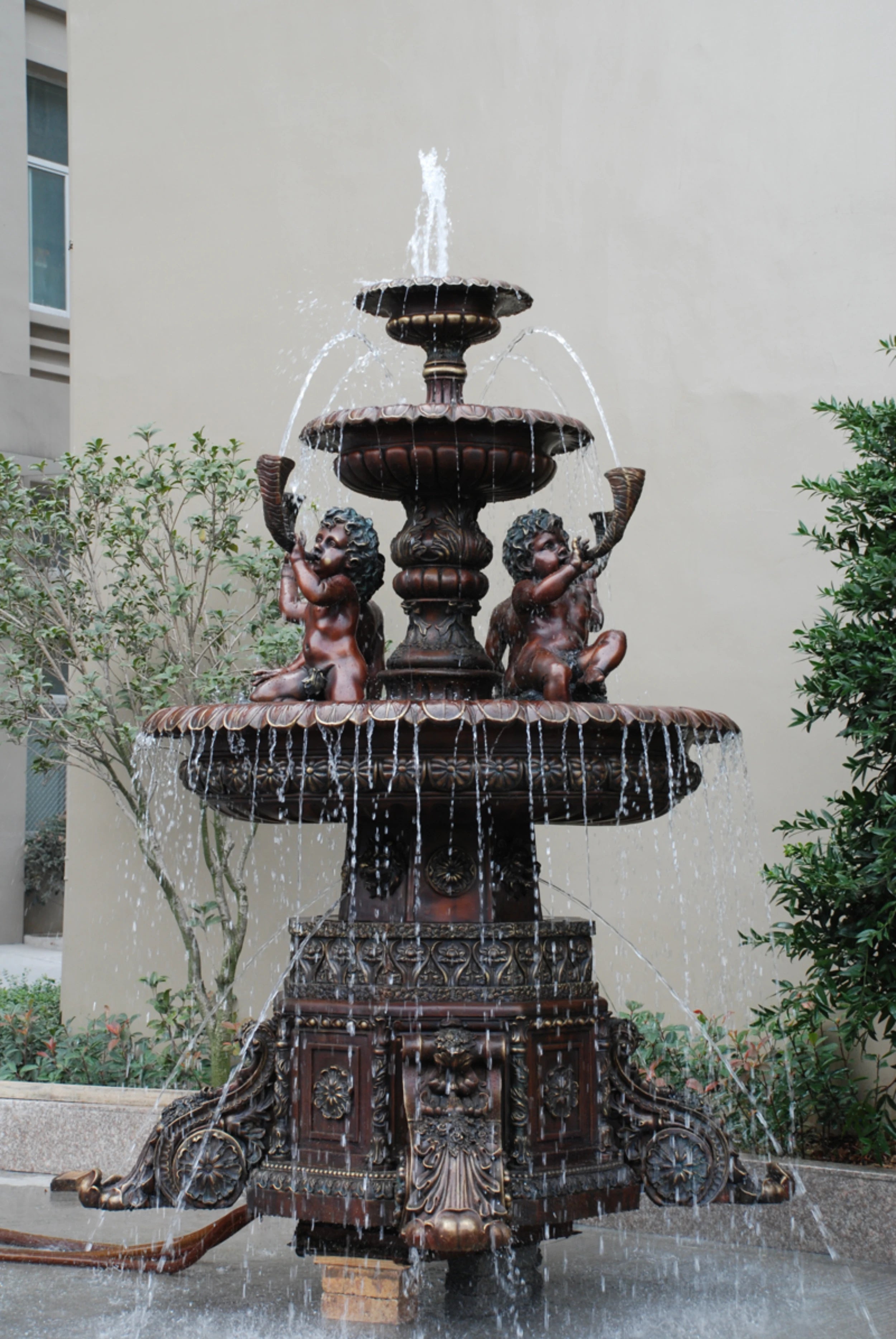 Large bronze cherub garden fountain with four angel figures and tiered water basins