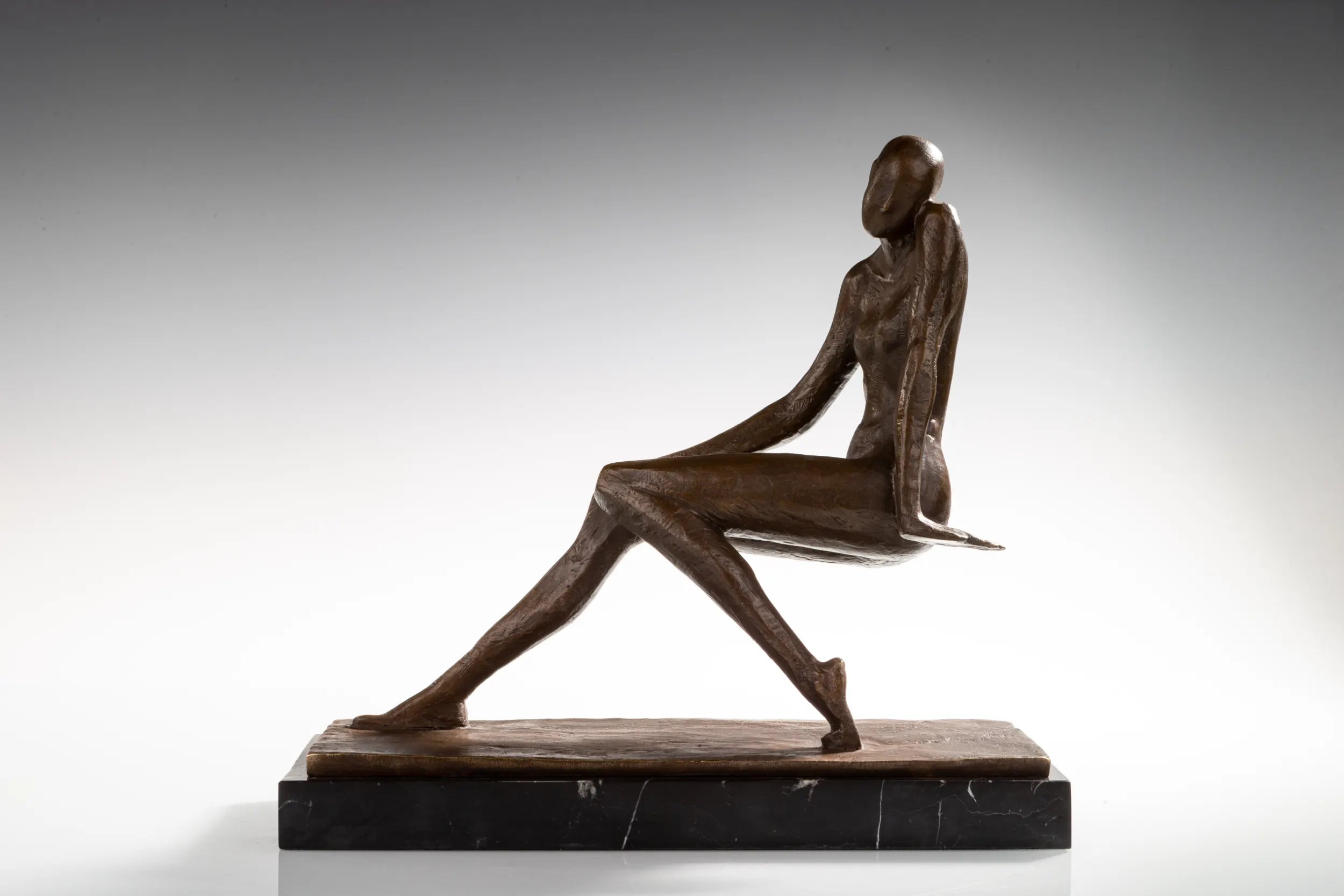 Opposite side view of listening woman bronze statue with one hand supporting her seated pose