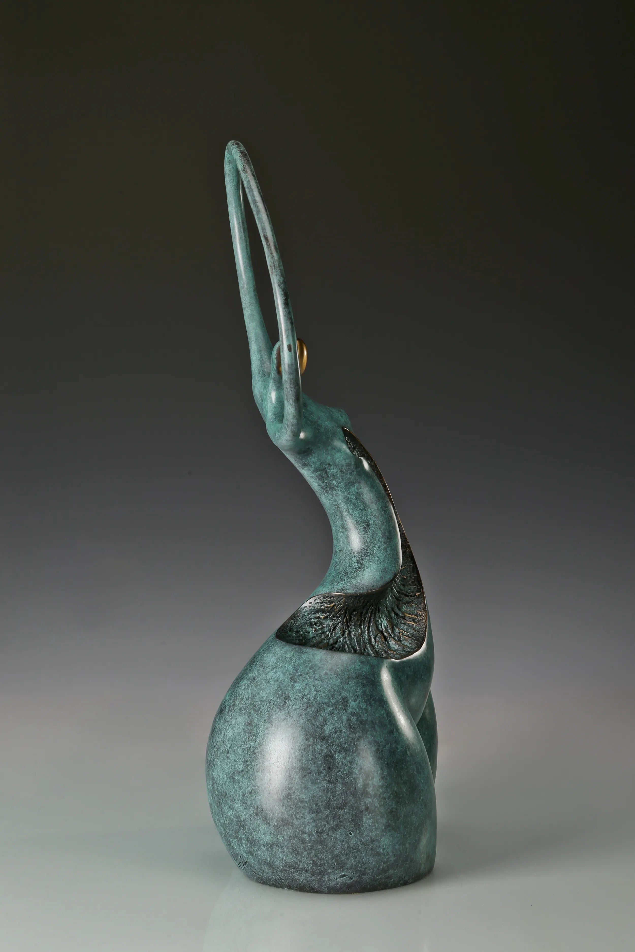 Narrow side view of modern bronze dancer sculpture with elongated curved design