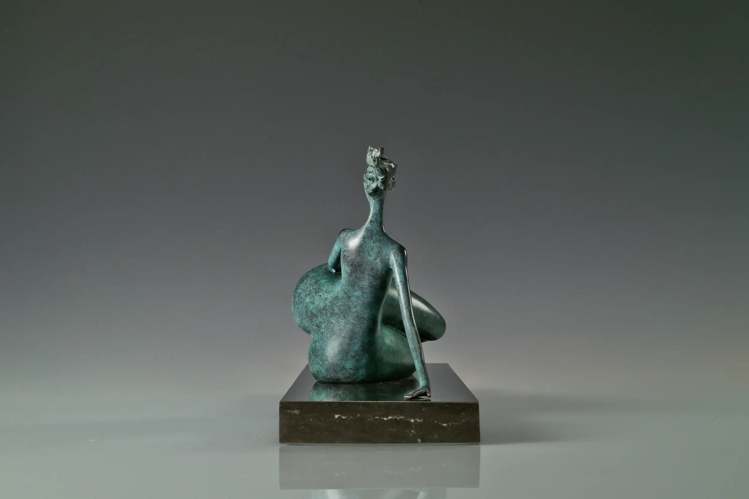 Reverse side of modern reclining woman bronze statue with extended legs