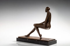 Full side view of modern seated woman bronze sculpture on a black marble base