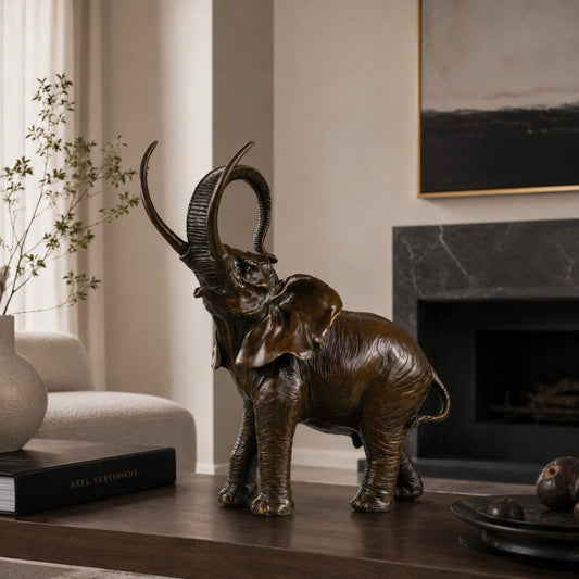 A highly detailed naturalistic bronze elephant sculpture with its trunk curled upward, a timeless symbol of strength and good fortune for office decor.