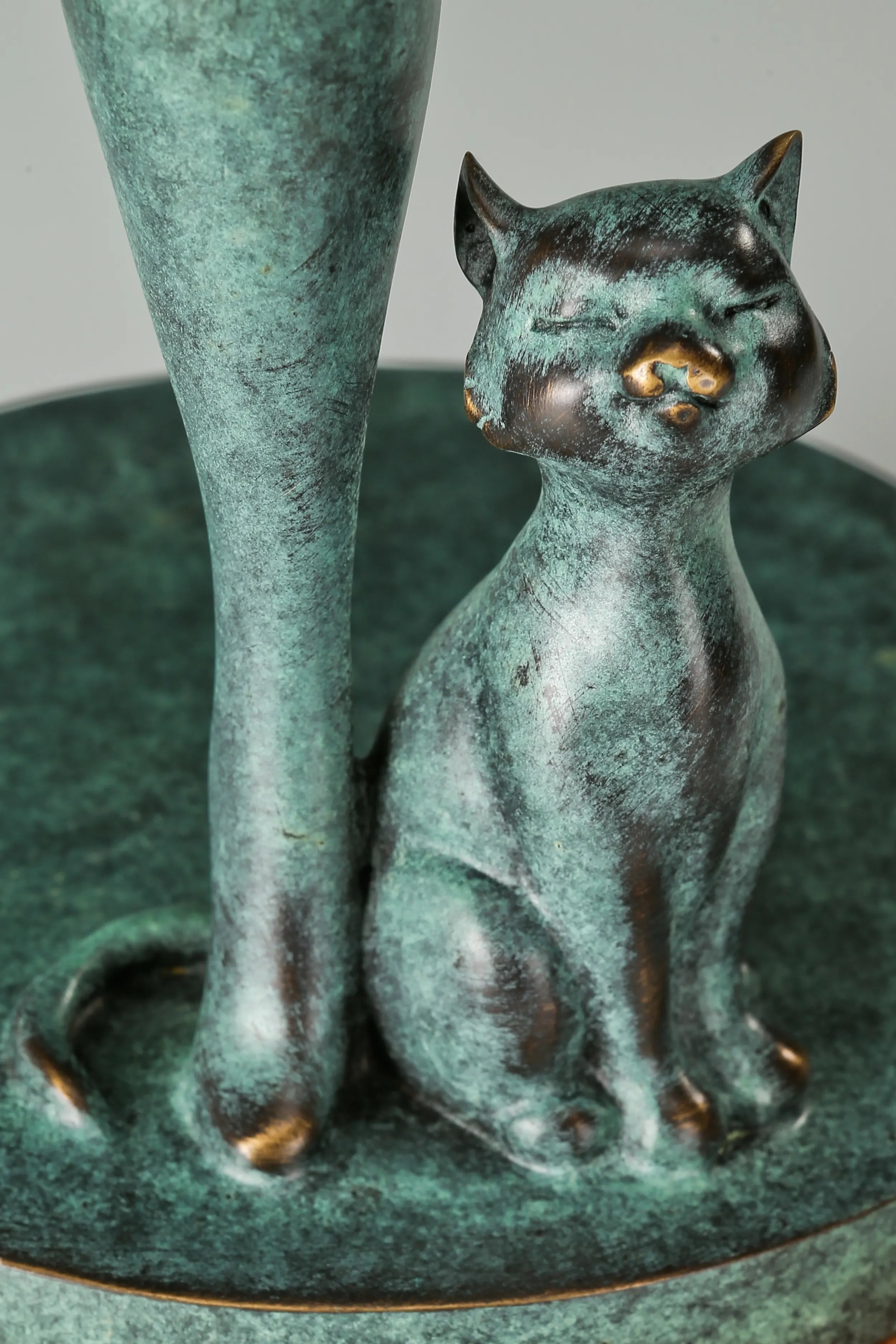 Close-up of the small seated bronze cat beside the musician's leg