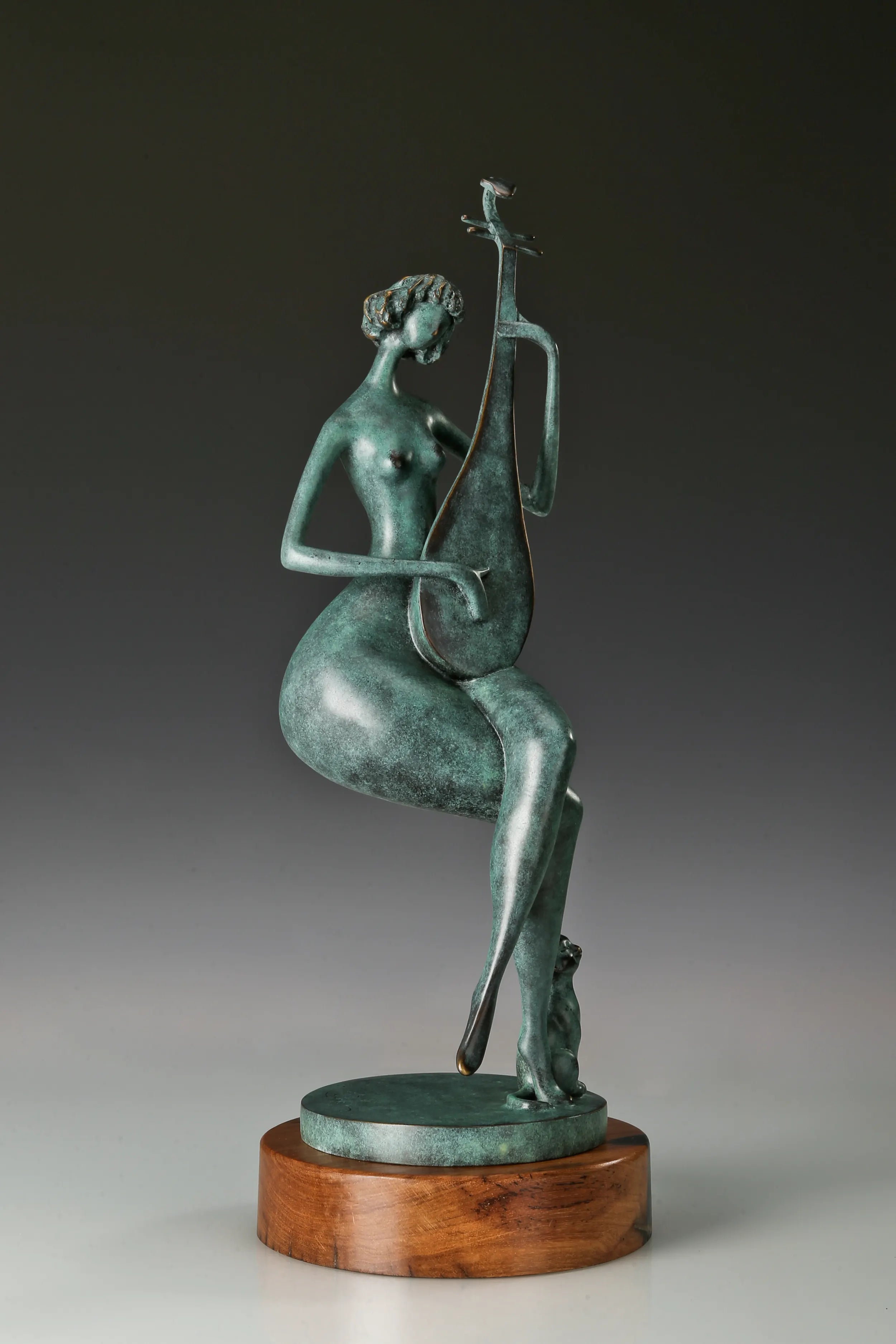 Three-quarter view of the green patina pipa player bronze sculpture with a cat beside her feet
