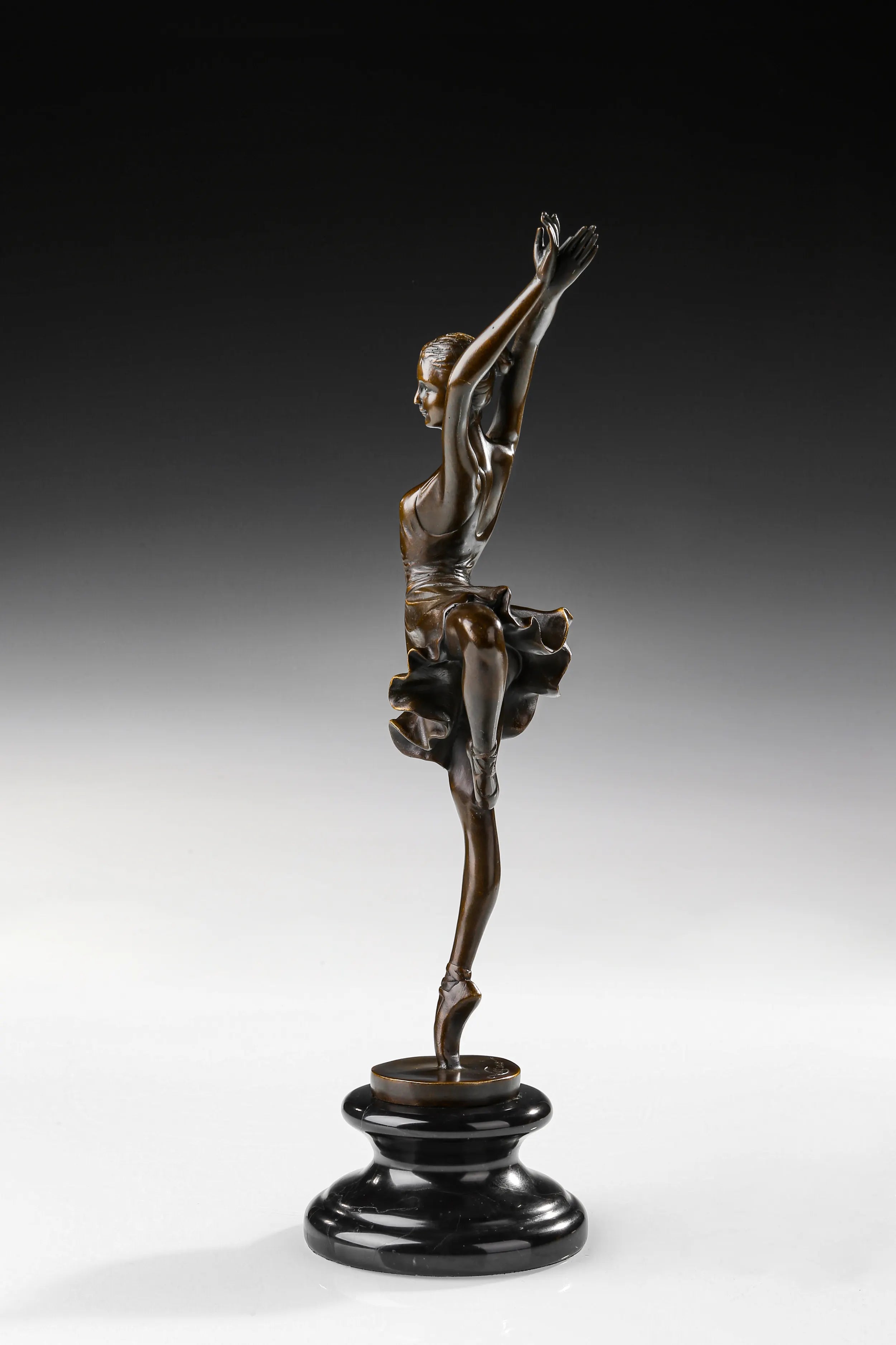 Left side view of bronze ballerina sculpture balancing with one bent leg raised