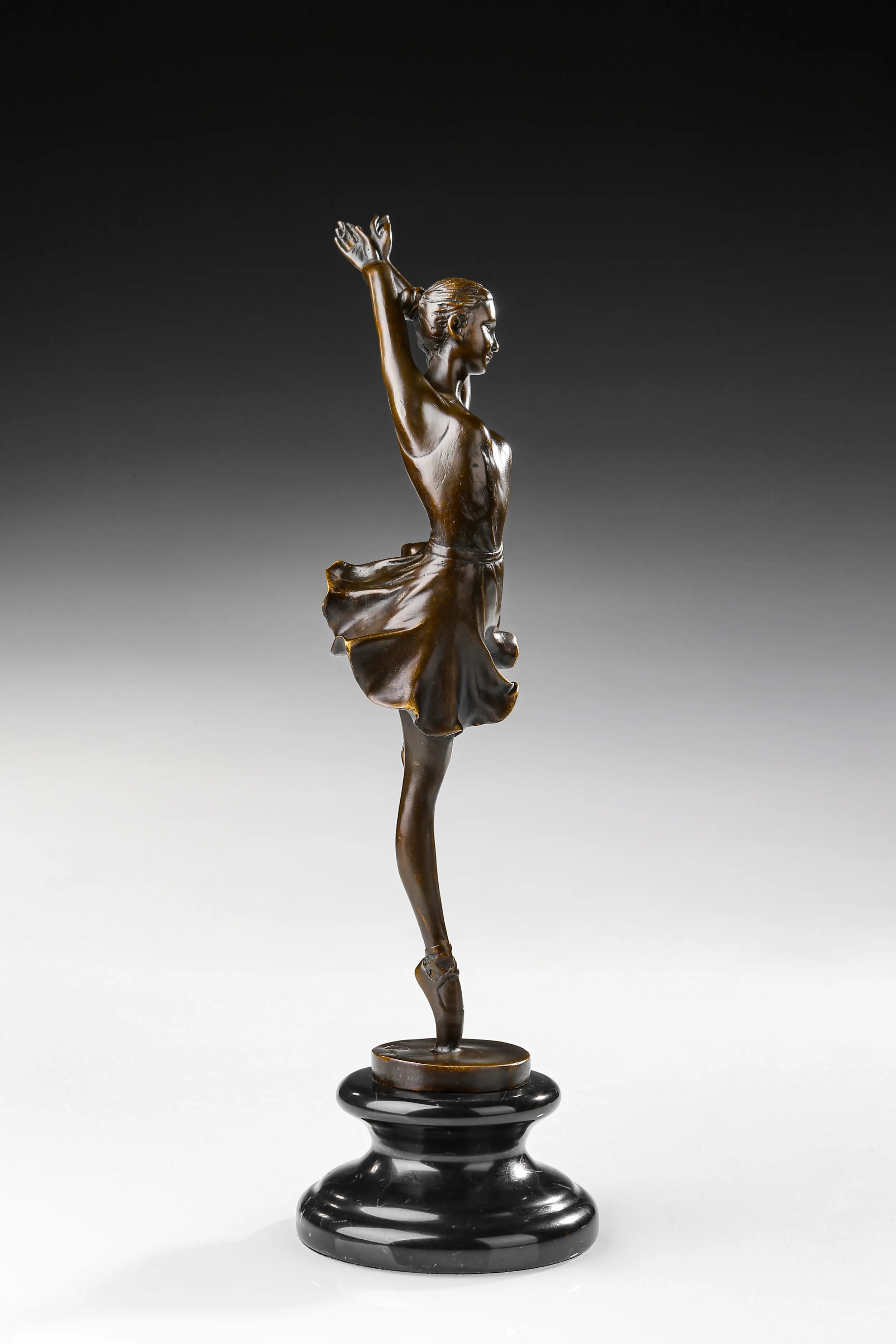 Right side view of raised leg ballerina bronze statue with a flowing skirt