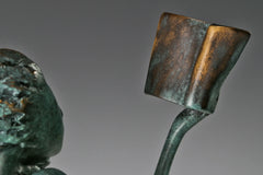 Close-up of the small open book held in the raised hand of the bronze reading woman