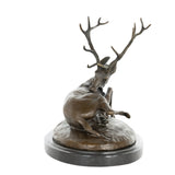 Front view of handcrafted reclining bronze deer sculpture with detailed branching antlers