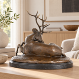 Reclining bronze deer sculpture displayed as elegant wildlife decor in a refined home or office interior