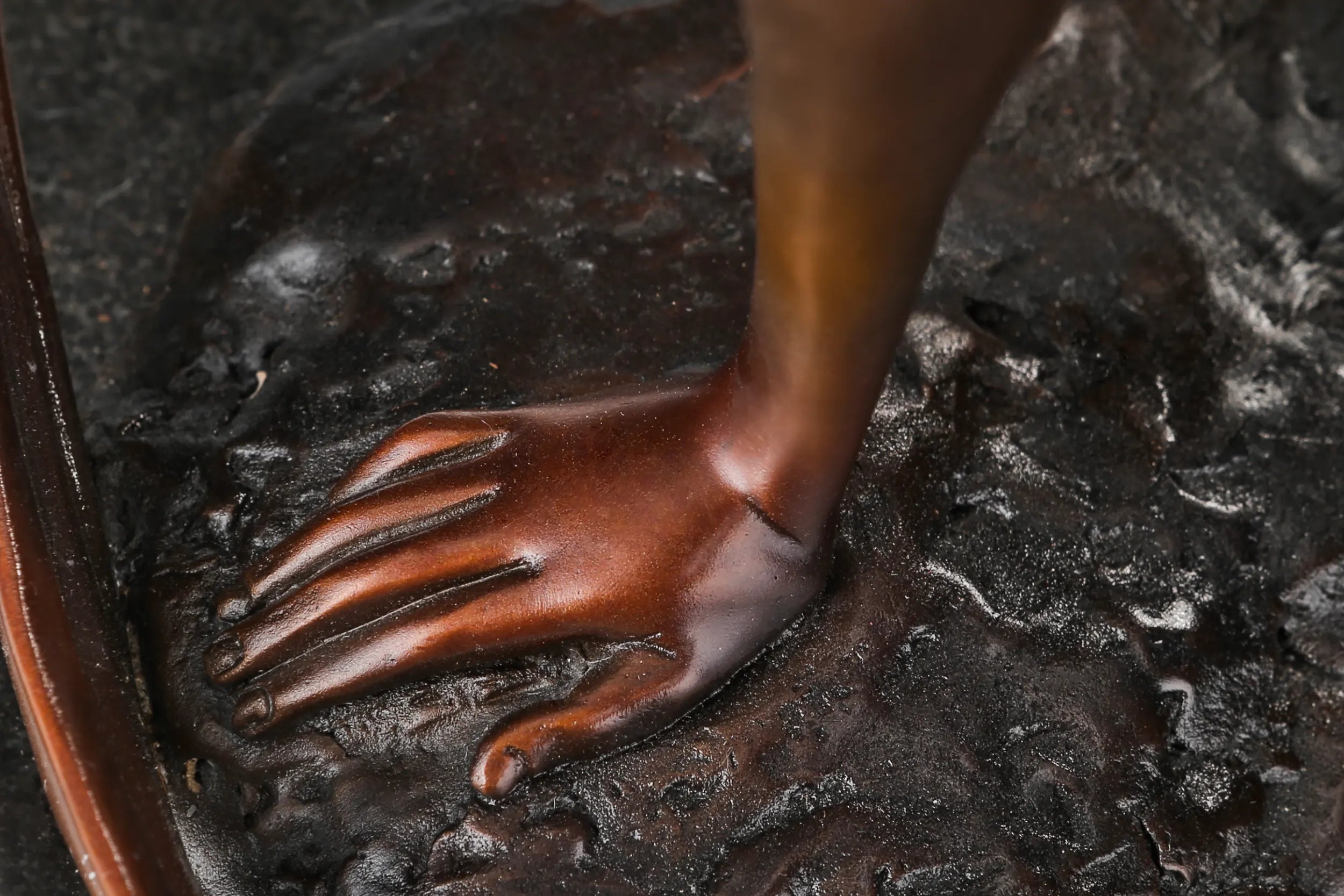 Close-up of the bronze ballet dancer's supporting hand resting on the textured base