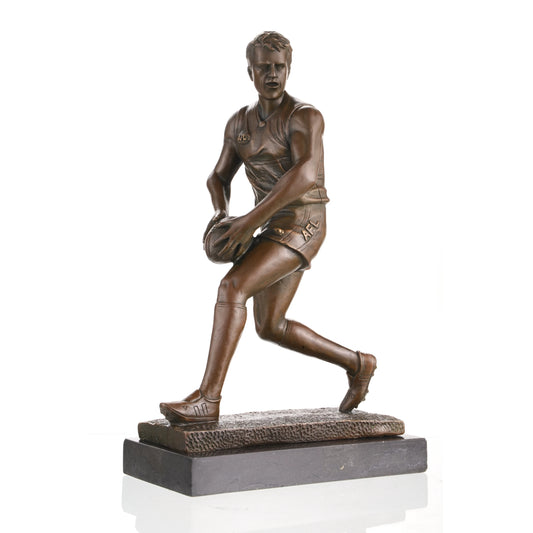 AFL football player bronze statue mid-run with oval ball, hyper-realistic Australian Rules Football statue on black marble base, loss wax casting sports art for trophies.