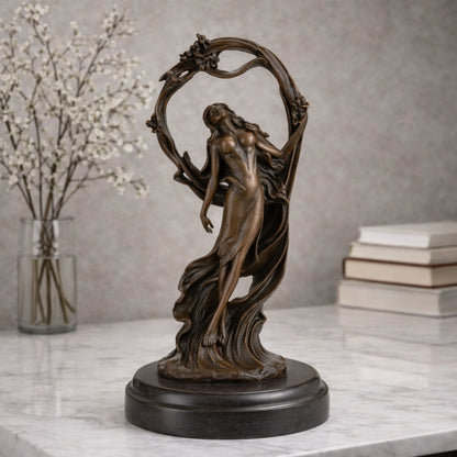 Art Nouveau bronze woman sculpture holding an orb, ethereal maiden statue with billowing gown and floral arch on black marble base, loss wax casting fine art.