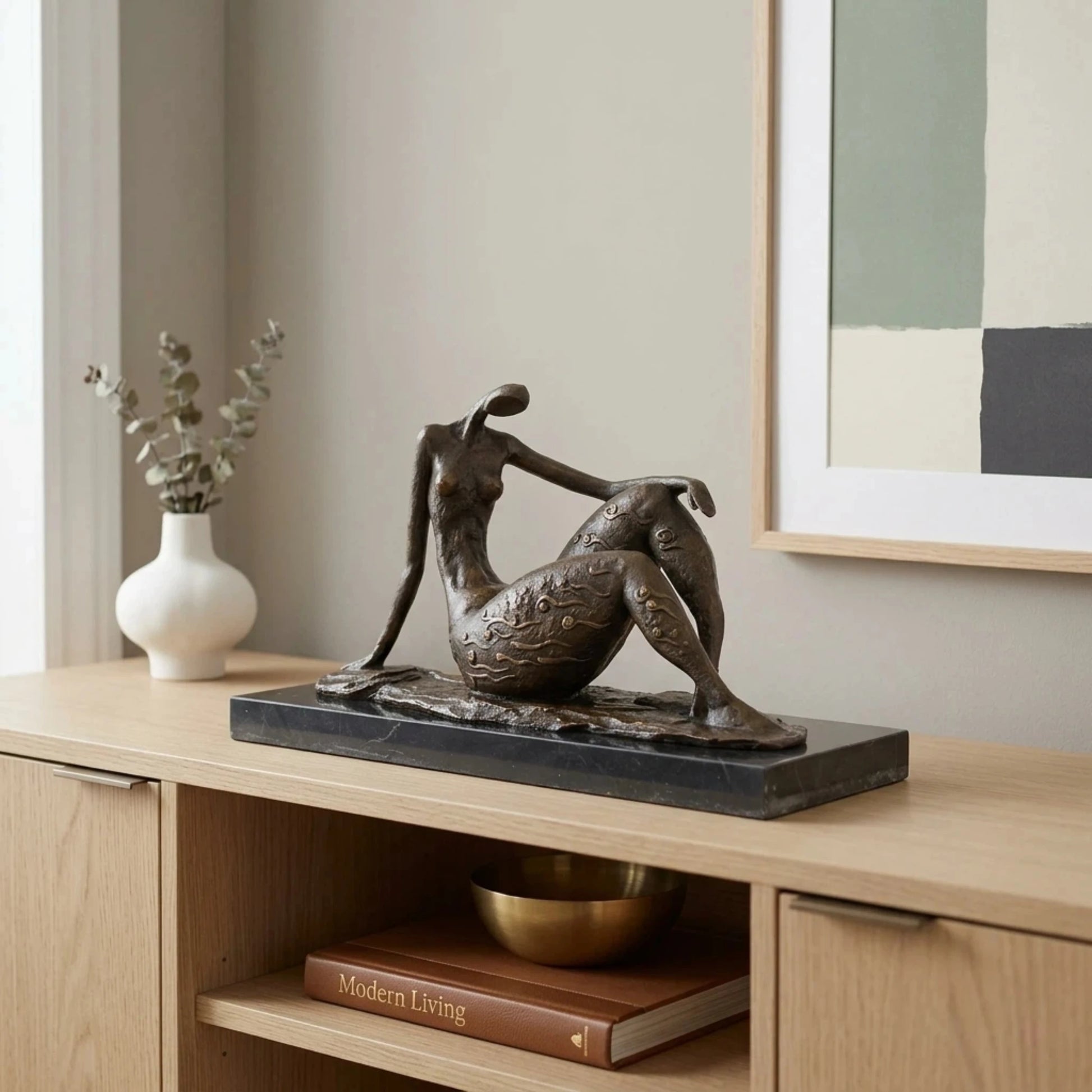 Contemporary abstract bronze seated female sculpture with golden swirls, faceless elongated woman statue on black marble base, loss wax casting modern art.