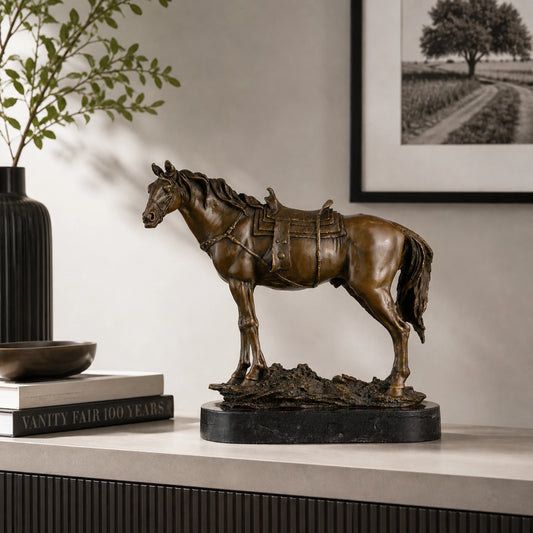 Saddled standing bronze horse sculpture with detailed tack and warm brown patina, realistic equestrian statue on black marble base, loss wax casting fine art.