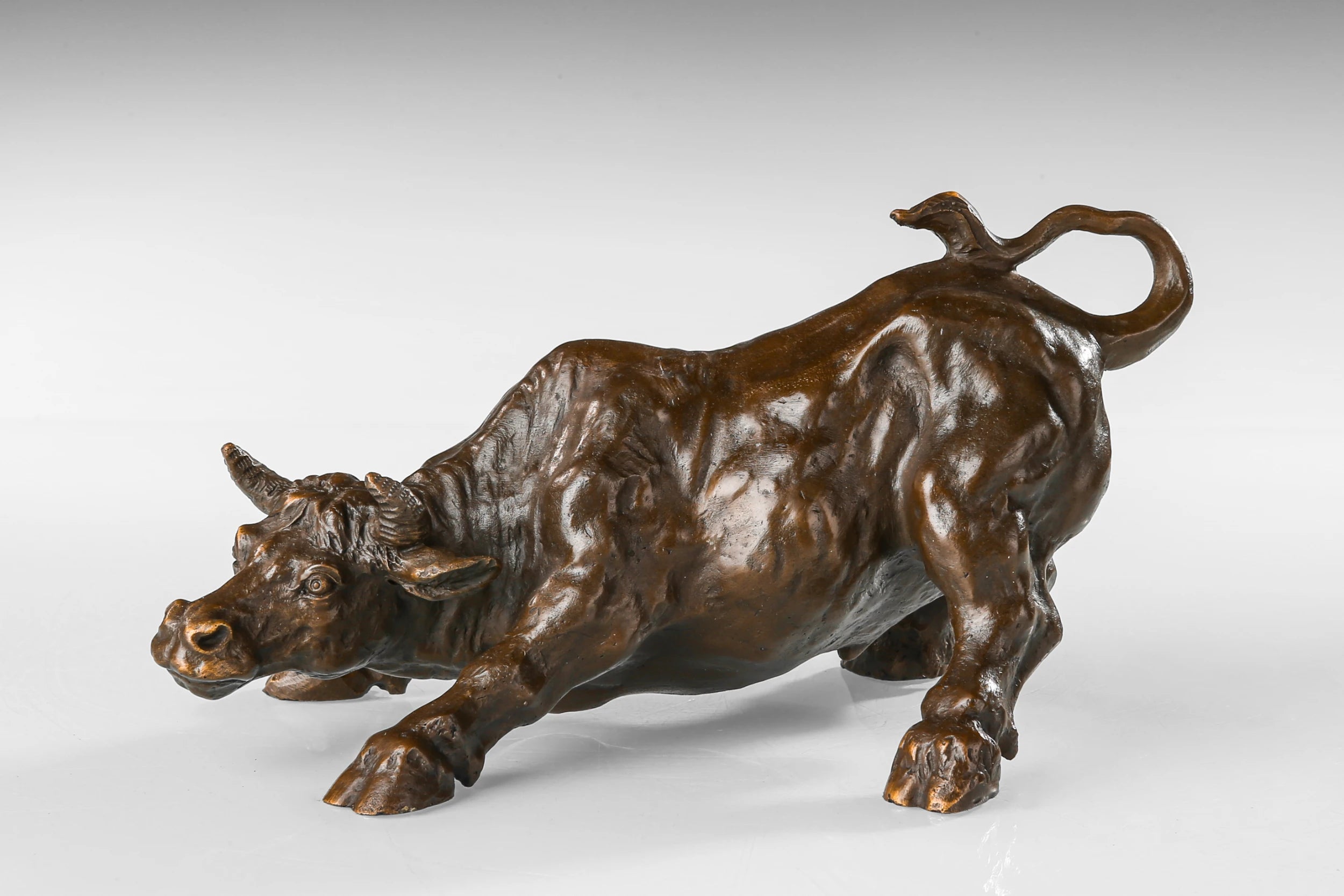Wall Street charging bull bronze sculpture in a powerful pose, realistic bull market statue, loss wax casting fine art.