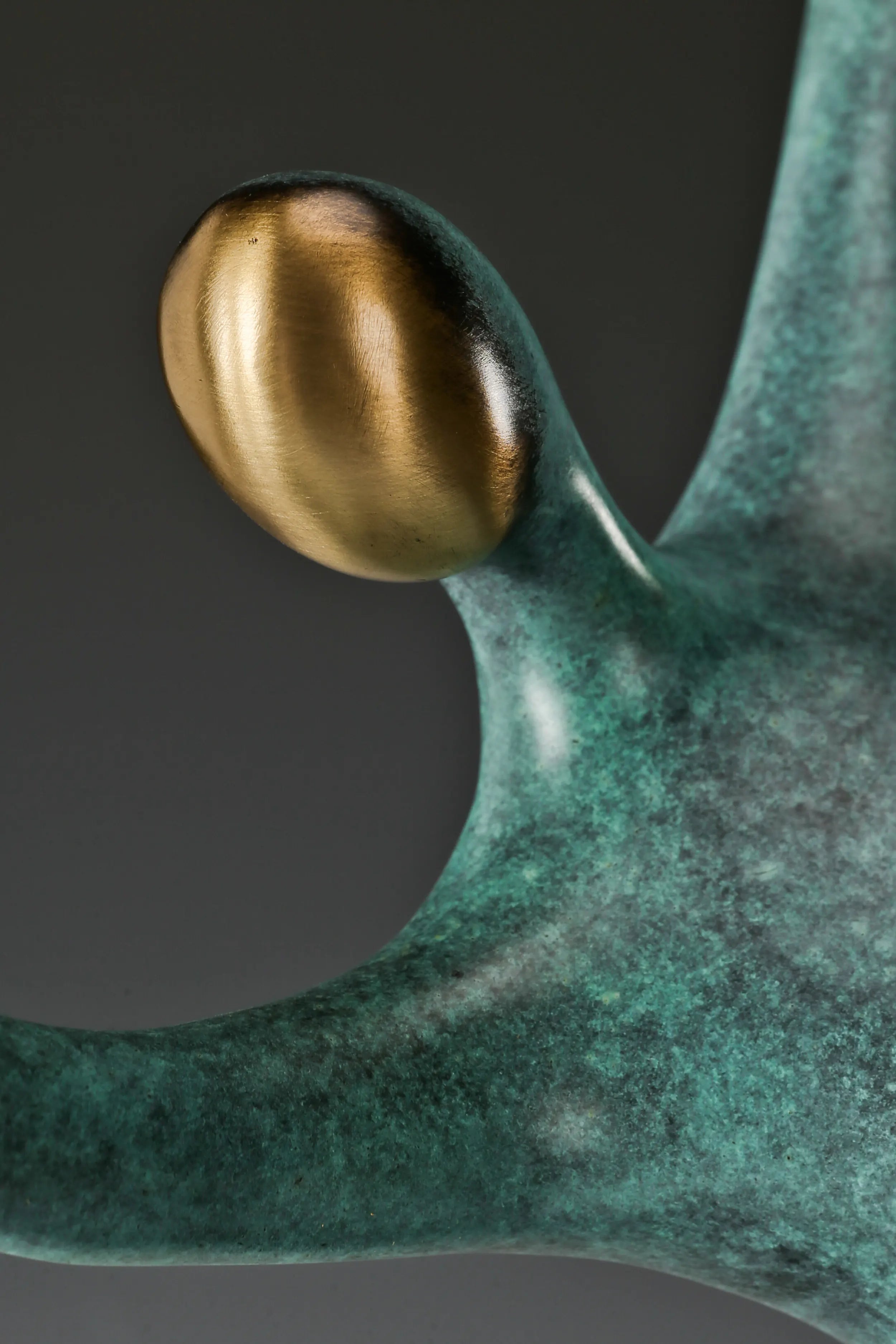 Close-up of the abstract bronze dancer's smooth gold-toned face