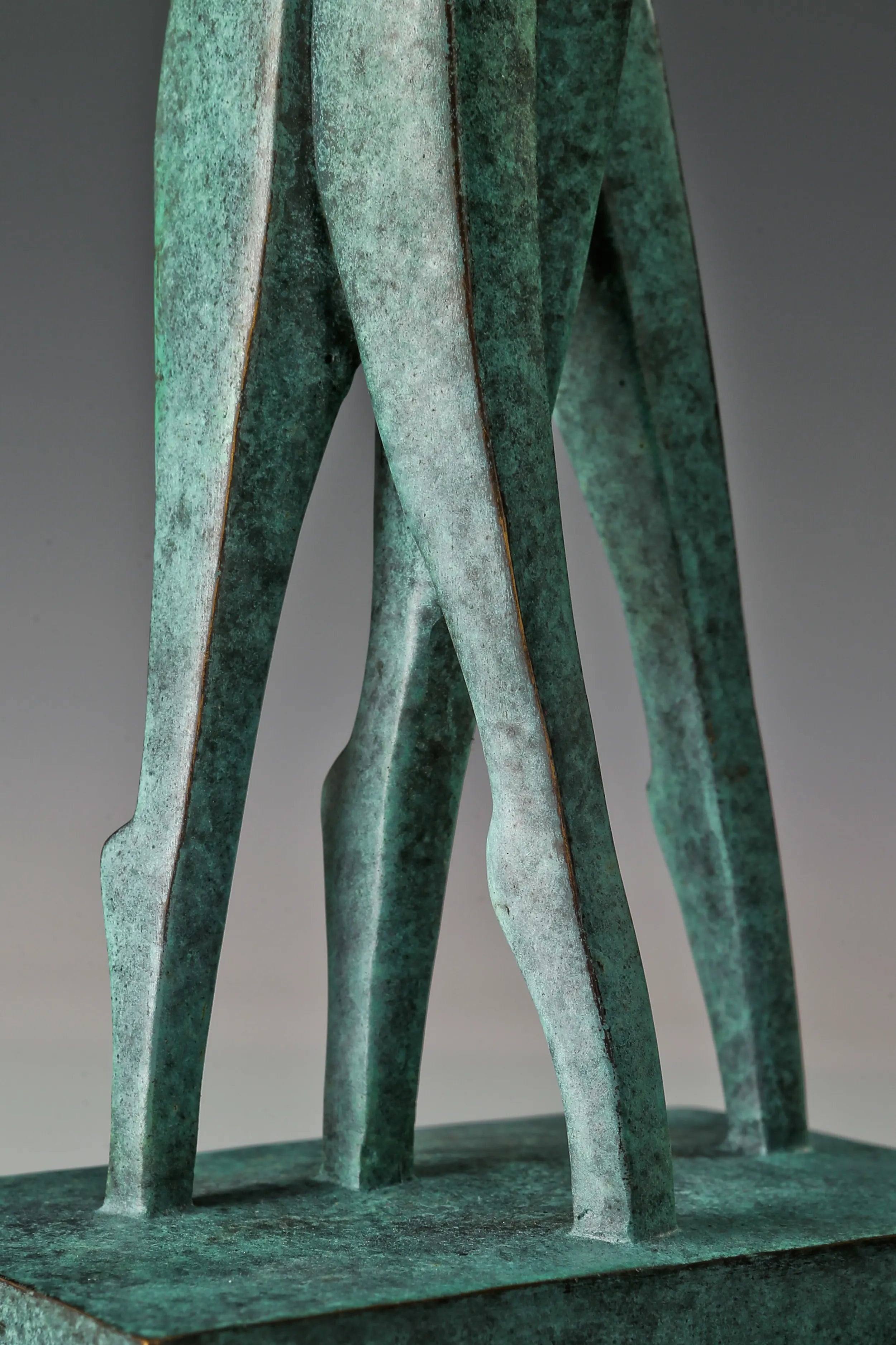 Close-up of the elongated bronze legs and textured green patina of the couple sculpture