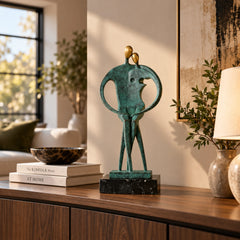Abstract couple bronze sculpture with golden faces displayed on a wooden console in a modern living room
