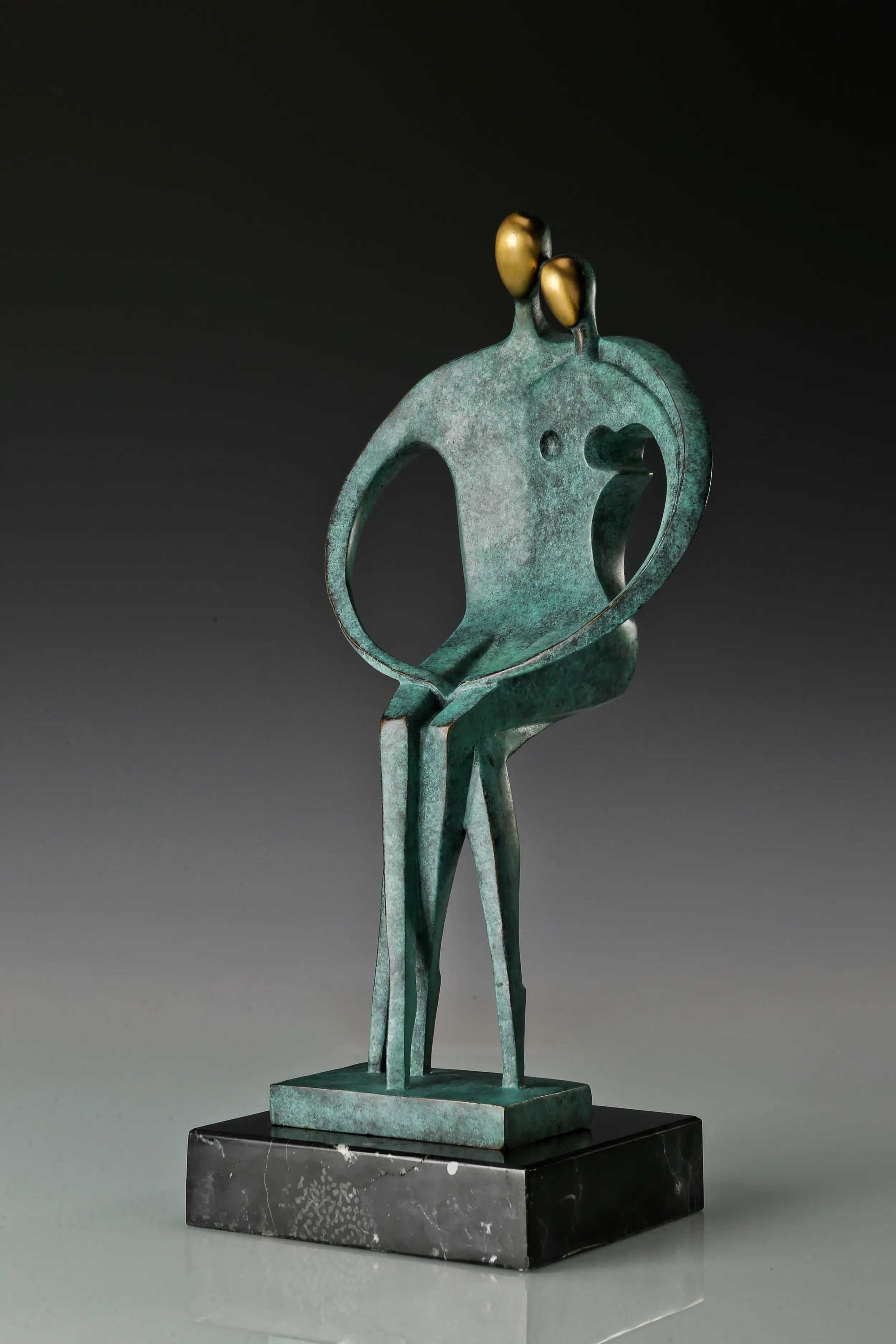 Right angled view of modern bronze lovers sculpture showing the curved arms and marble base