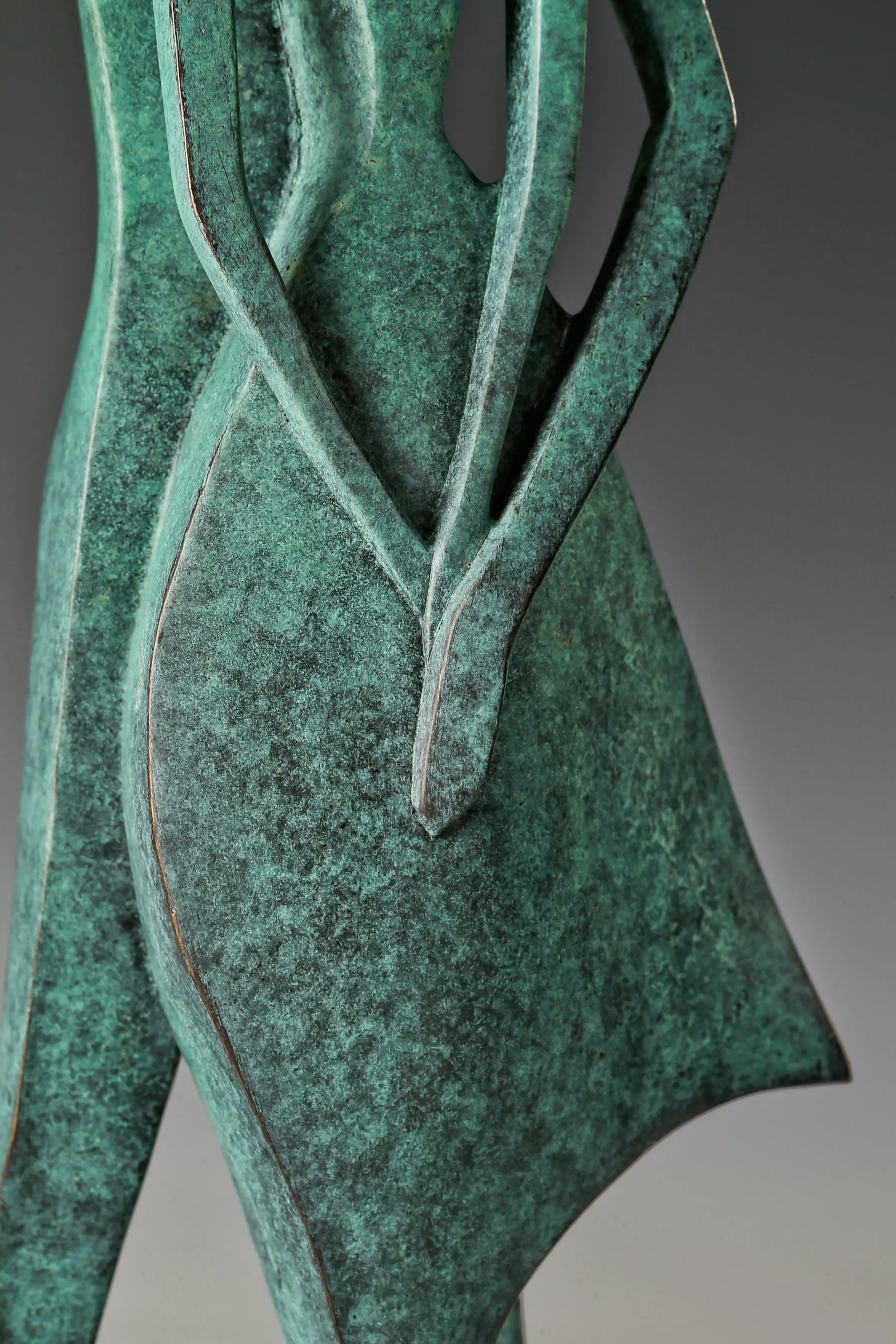Close-up of the overlapping arms and bodies of the abstract bronze couple